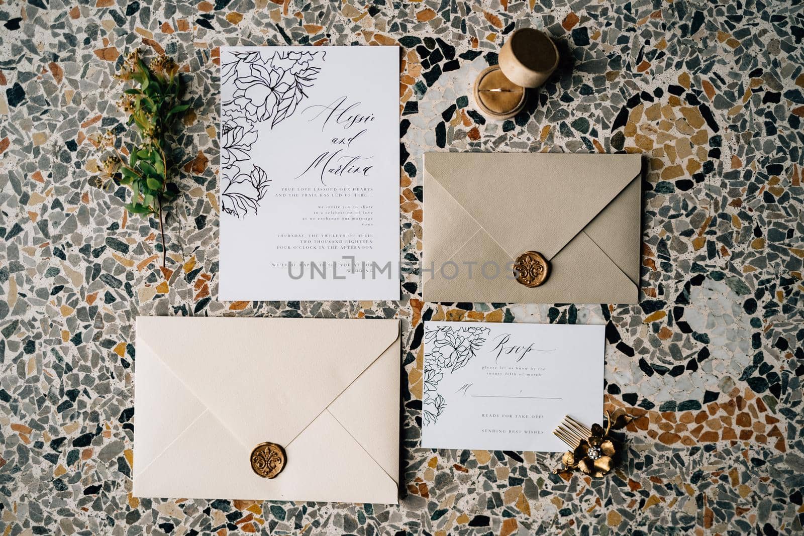 Envelopes and invitations sealed with sealing wax lie on the mosaic tiles. Nearby lies a green twig and a flower-shaped hairpin. High quality photo