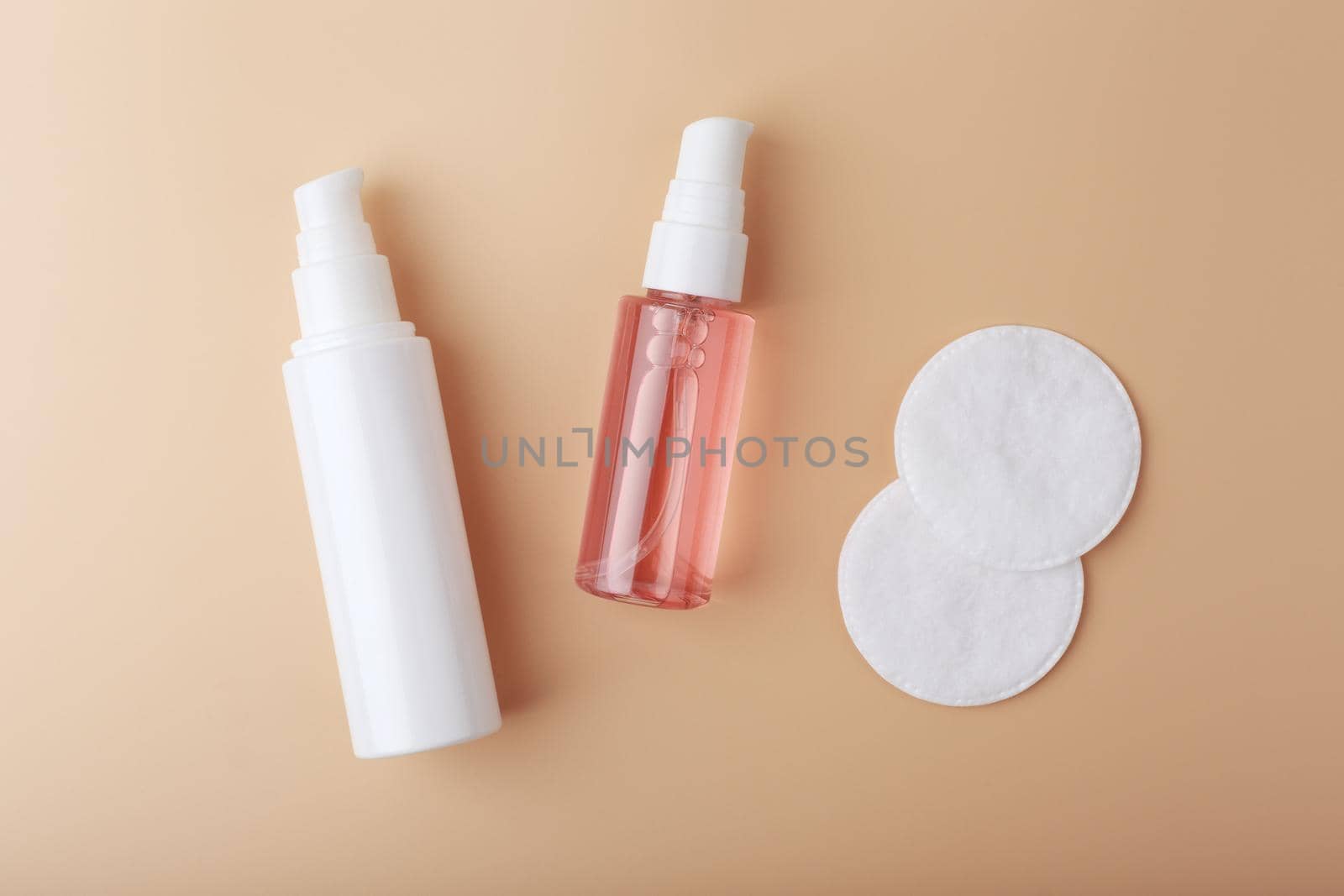 Face cream or lotion and make up removing foam with cotton pads on beige background. Top view of beauty products for skin cleaning and make up removing. Concept of skin care products