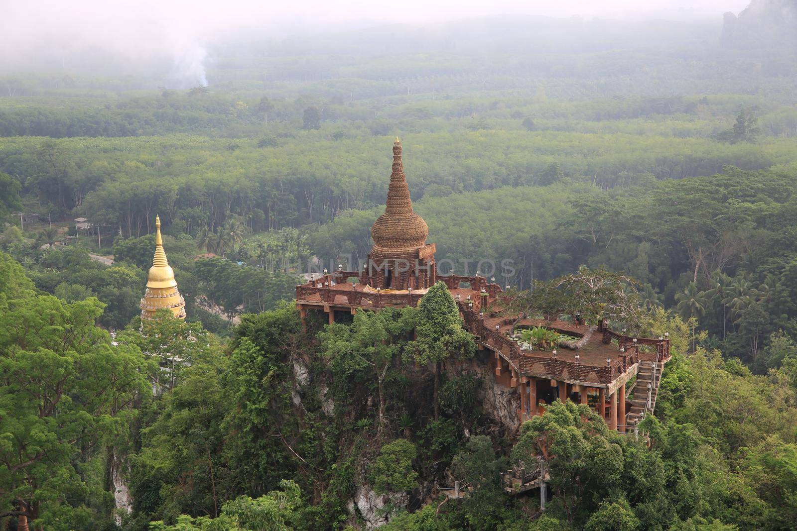 Landscape of beautiful sunrise with pagoda on peak mountain and tree with misty morning at Na Nai Luang temple , Surat Thani Province, Southern of Thailand