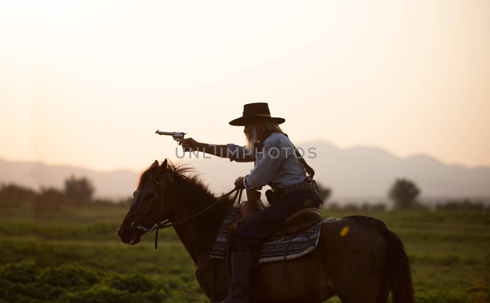 cowboy on horseback against a beautiful sunset, cowboy and horse at first light,mountain, river and lifestyle with natural light background. by chuanchai