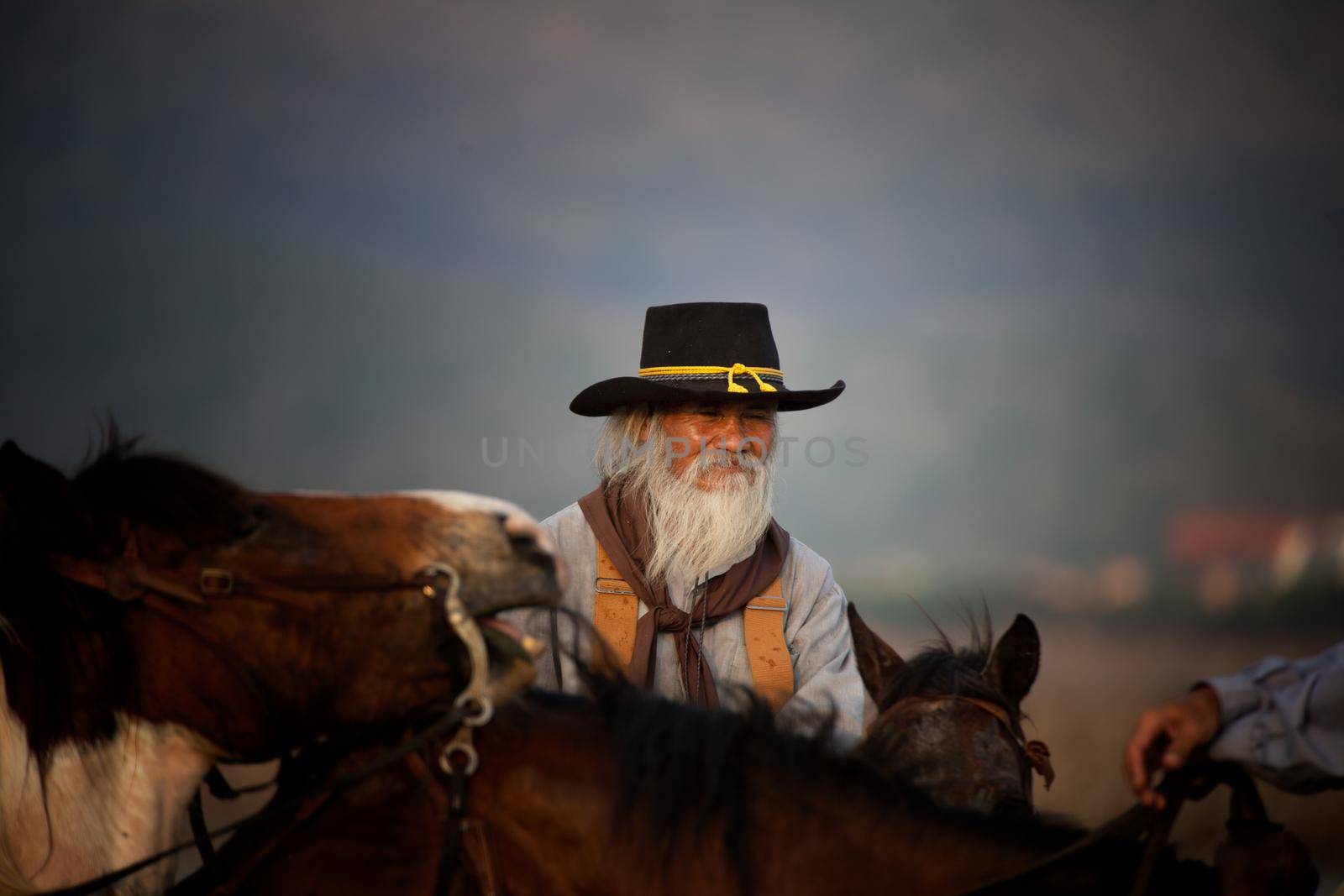 cowboy on horseback against a beautiful sunset, cowboy and horse at first light,mountain, river and lifestyle with natural light background. by chuanchai