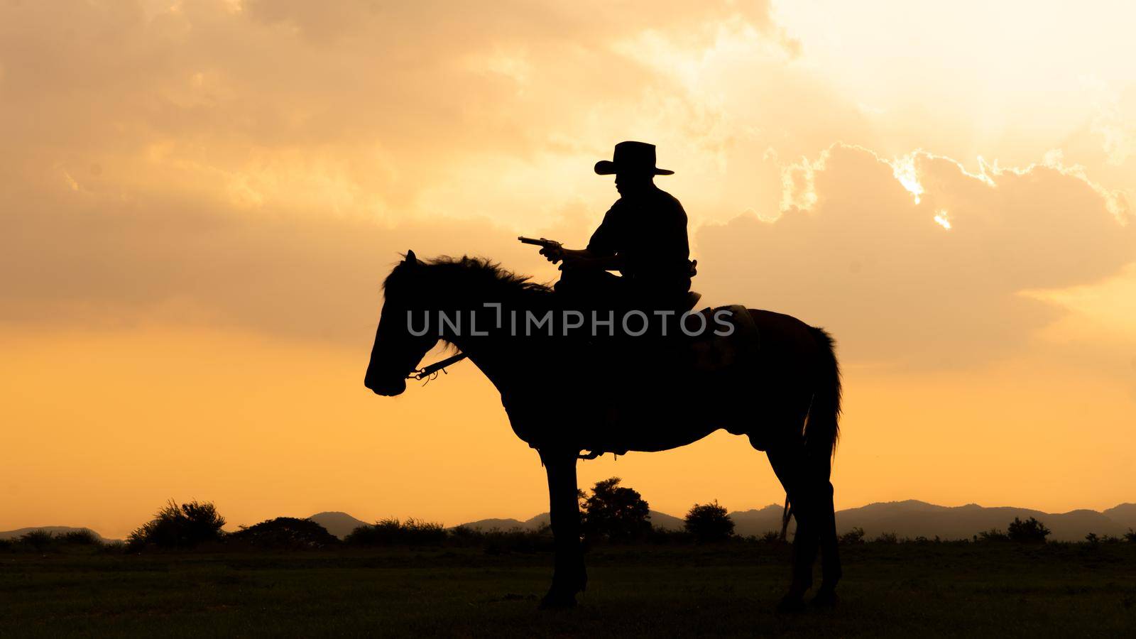 cowboy on horseback against a beautiful sunset, cowboy and horse at first light,mountain, river and lifestyle with natural light background	
