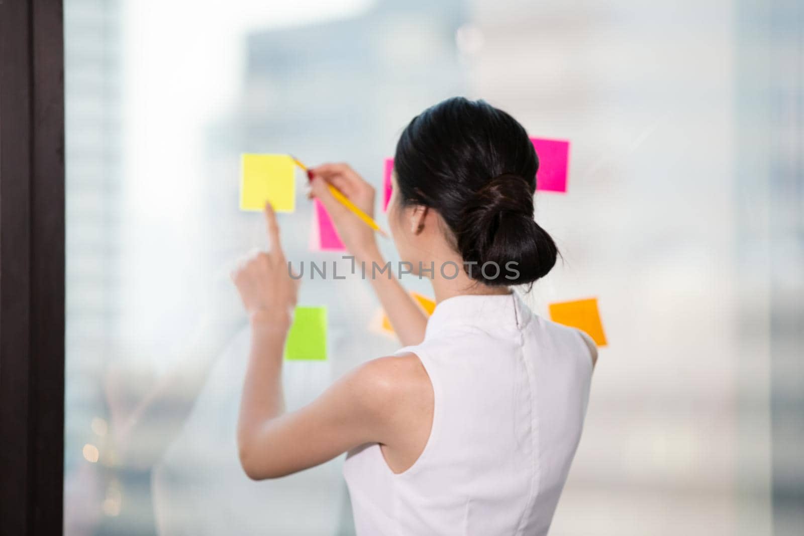Business woman Write notes on the paper attached to the window glass.