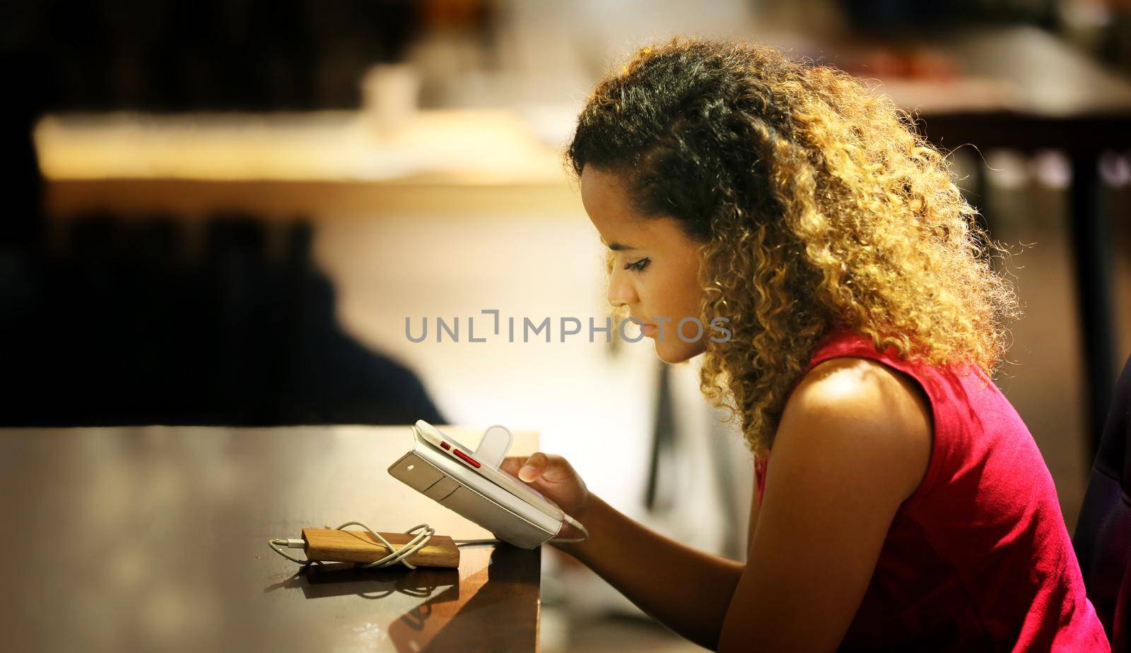 woman texting on mobile phone in café. by chuanchai