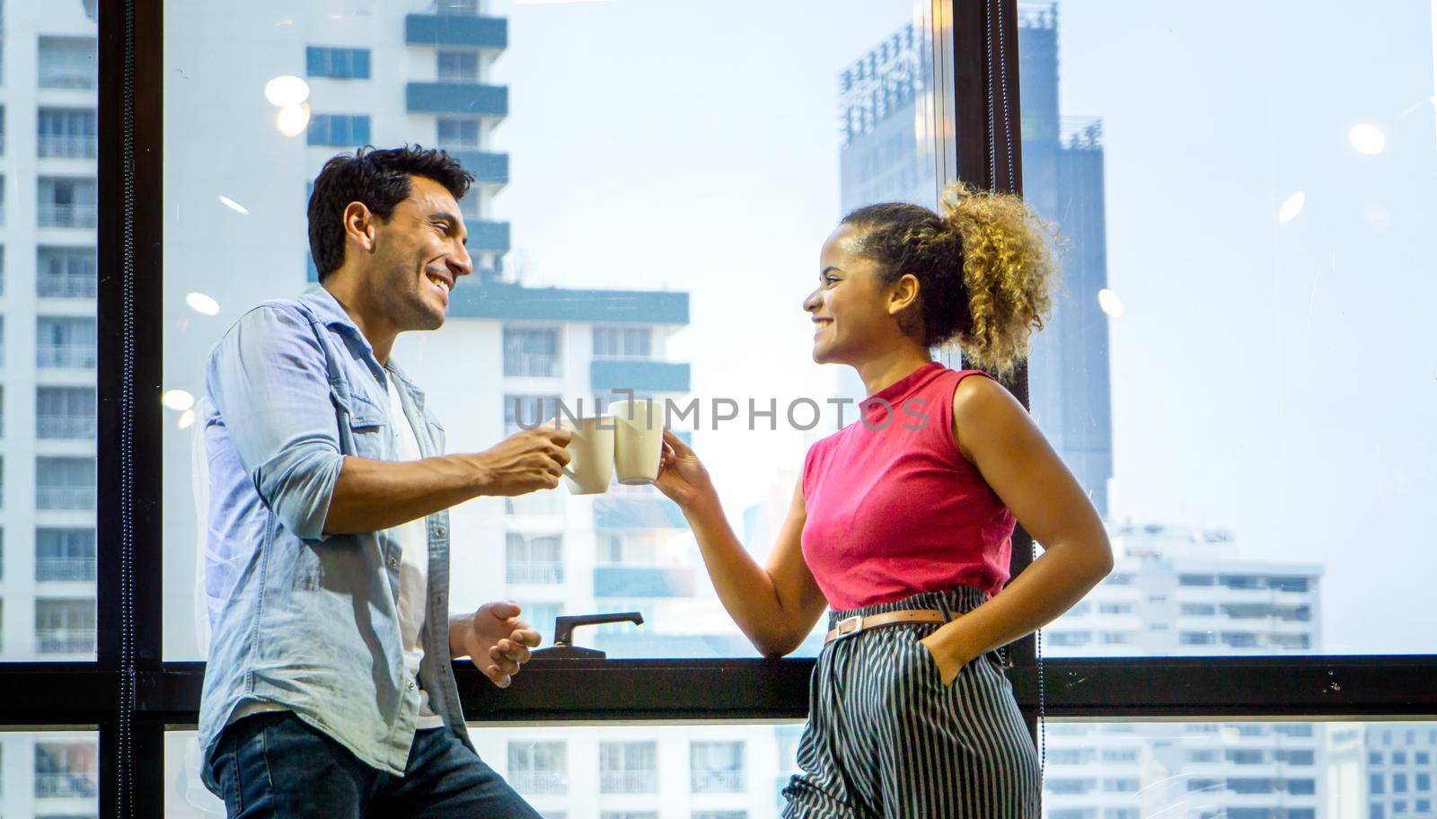 Happy young couple is drinking coffee and smiling while standing at the café