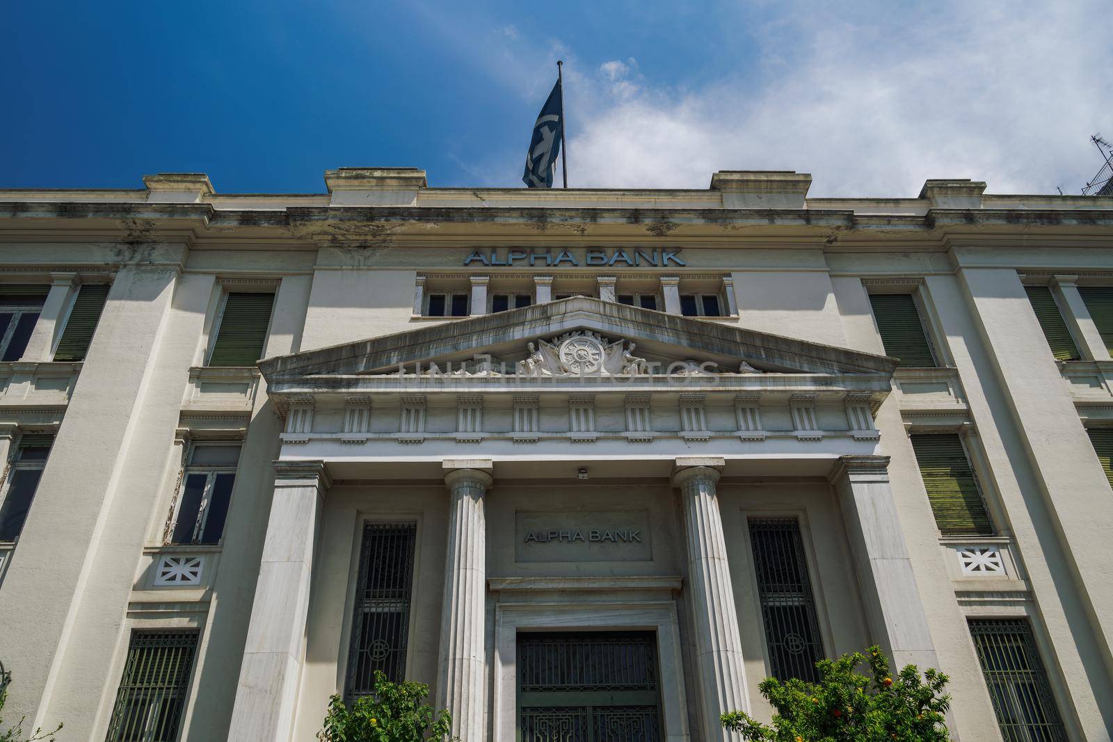 Day view of neoclassical monument of branch of Alpha Bank Greece with sign at Mitropoleos street.