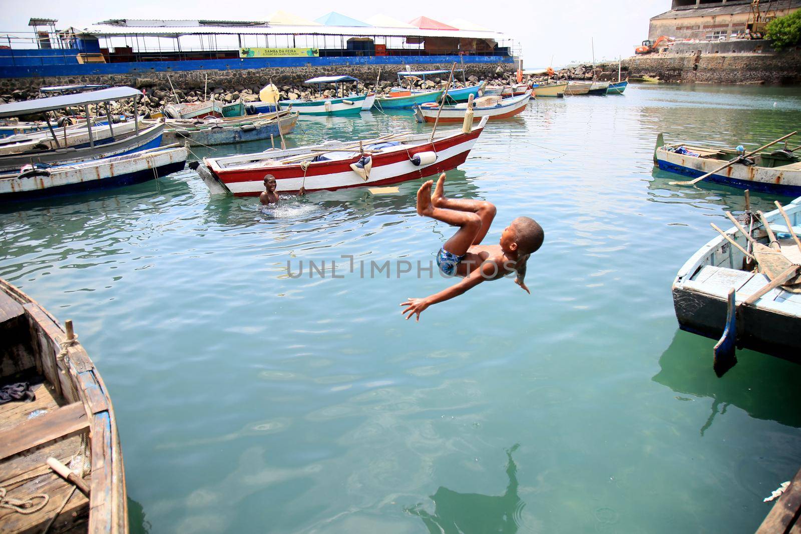 salvador, bahia, brazil - february 17, 2021: children playing next to boats in the port of Sao Joaquim fair in the city of Salvador.