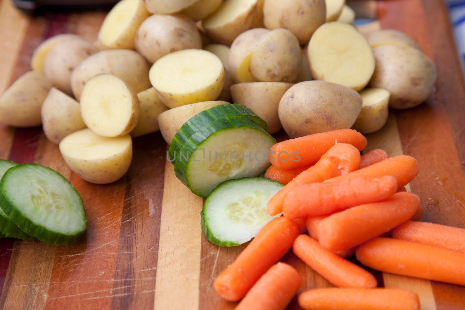 Freshly cut carrots, potatoes and cucumbers on a wooden board