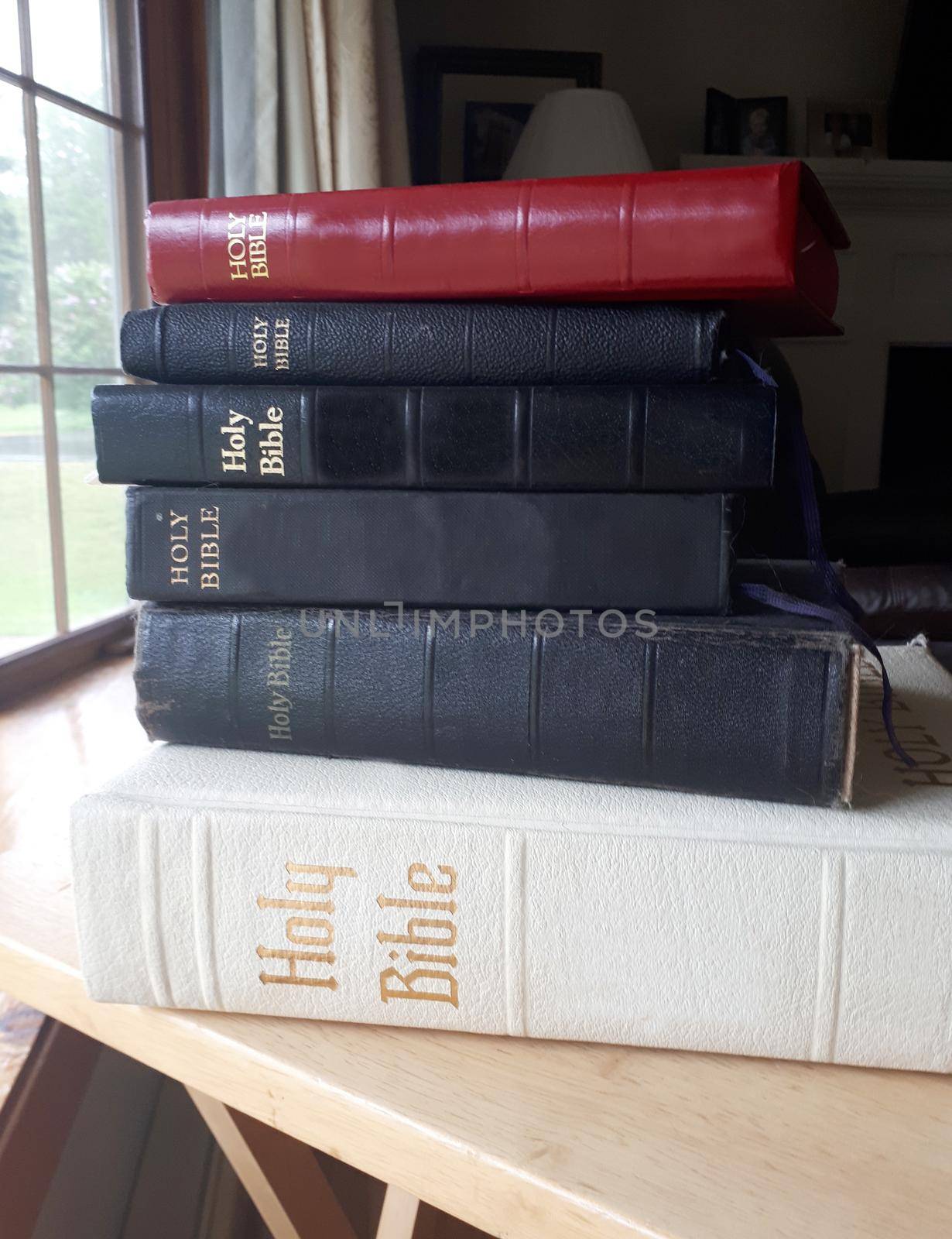  Five bibles stacked up on a table 