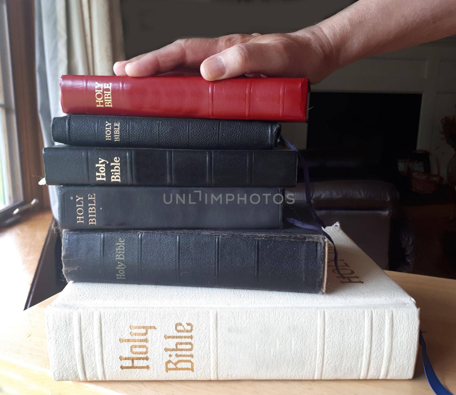 A hand on top of a stack of bibles is ready to swear the truth 