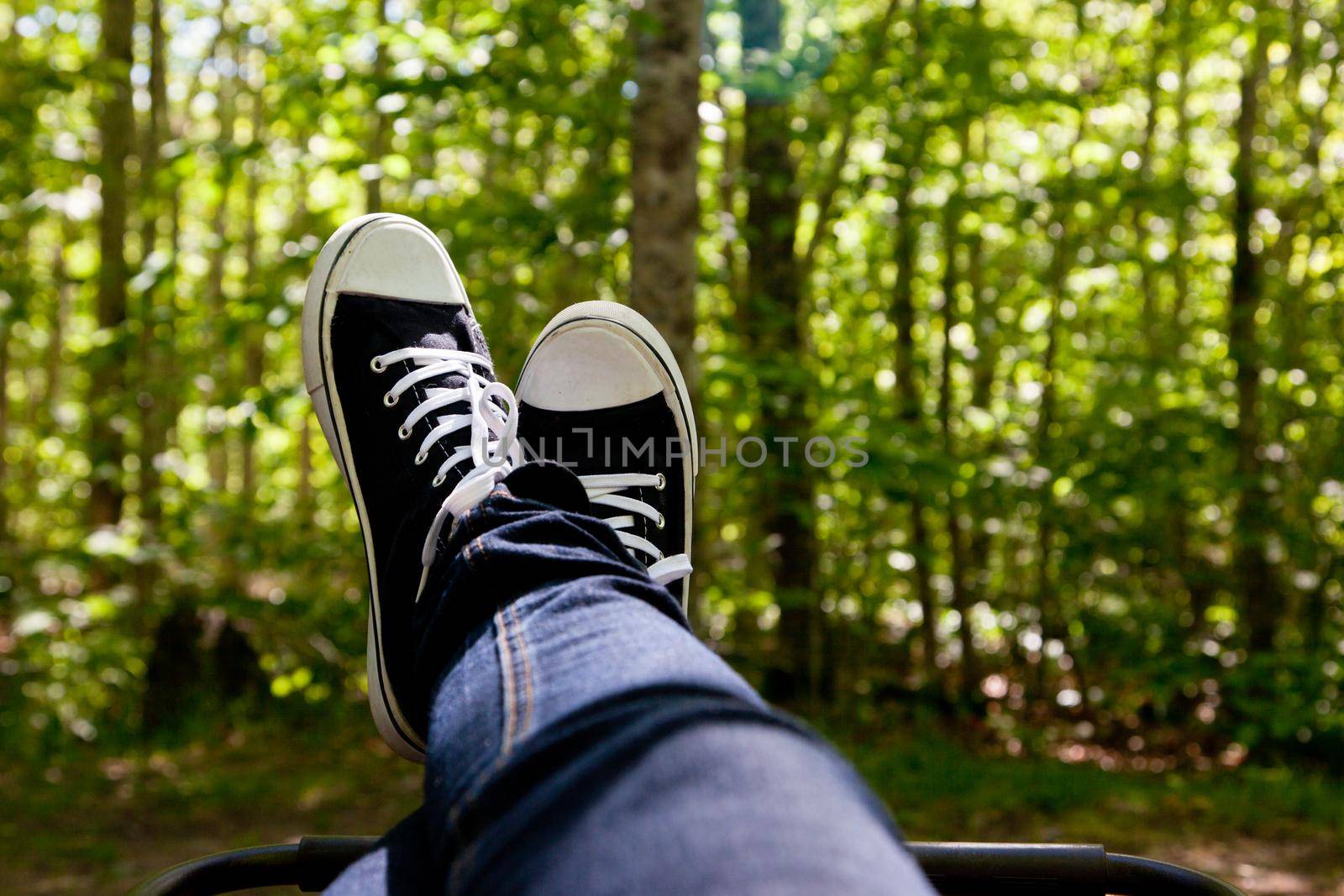 Sneakers are up, a person is relaxed at their camp site in the forest or woods 
