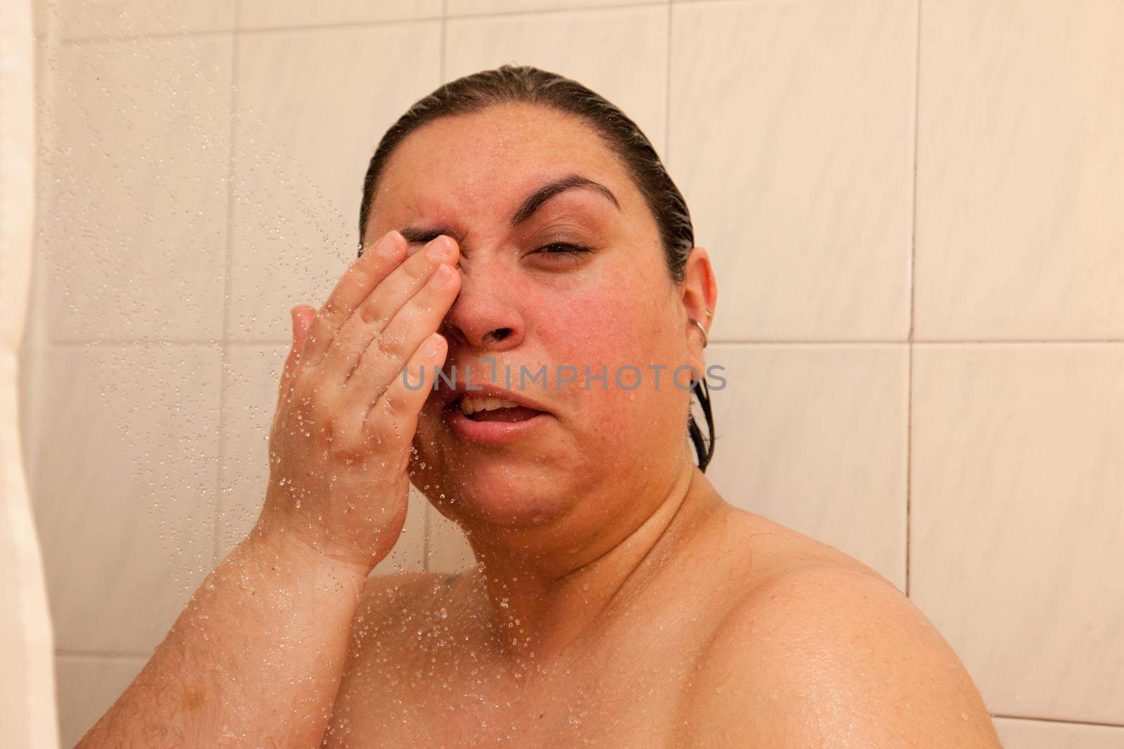 A woman makes a pained expression because she has water in her eye 