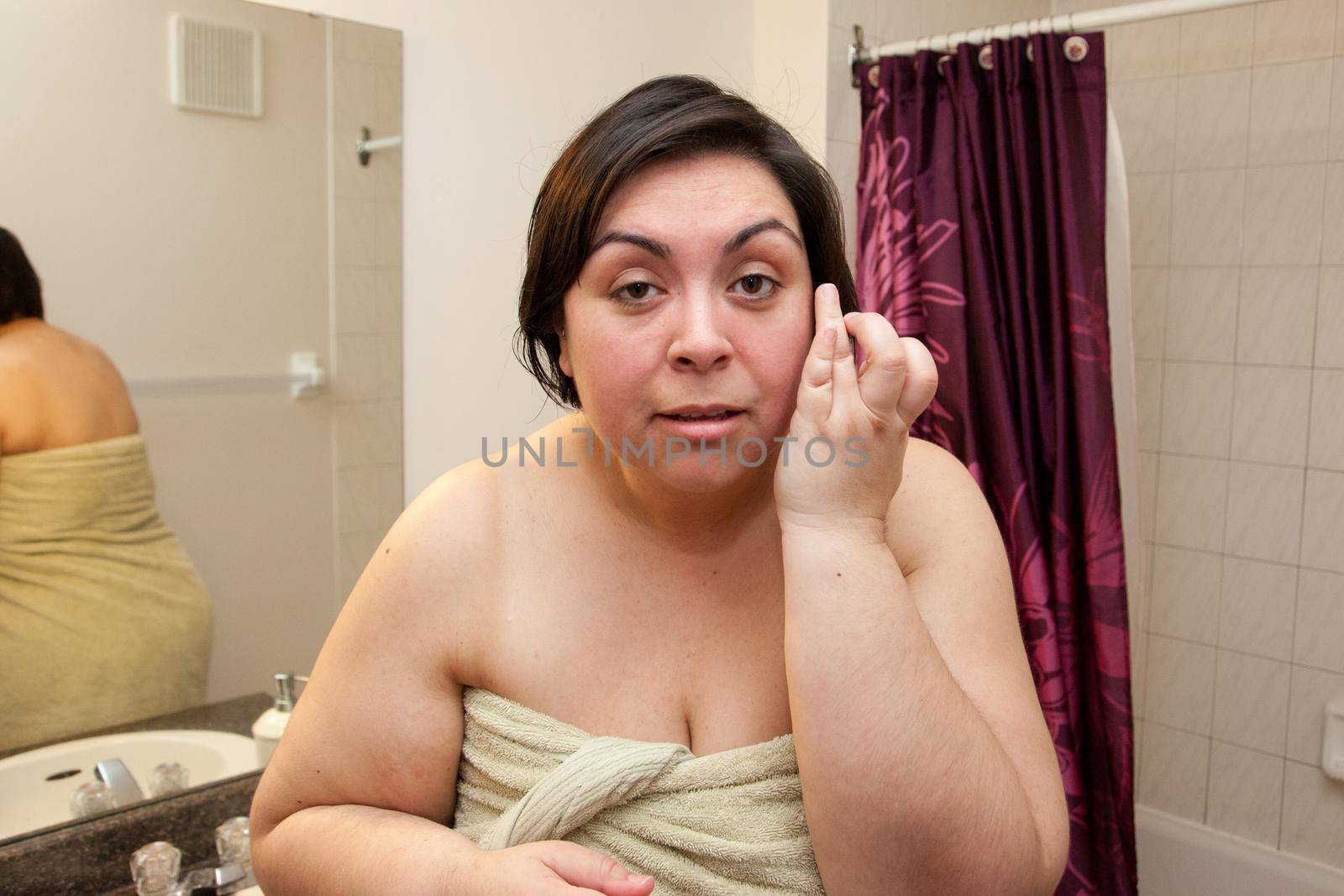  Woman out of the shower looks at herself with camera point of view, and touches her face checking her skin 