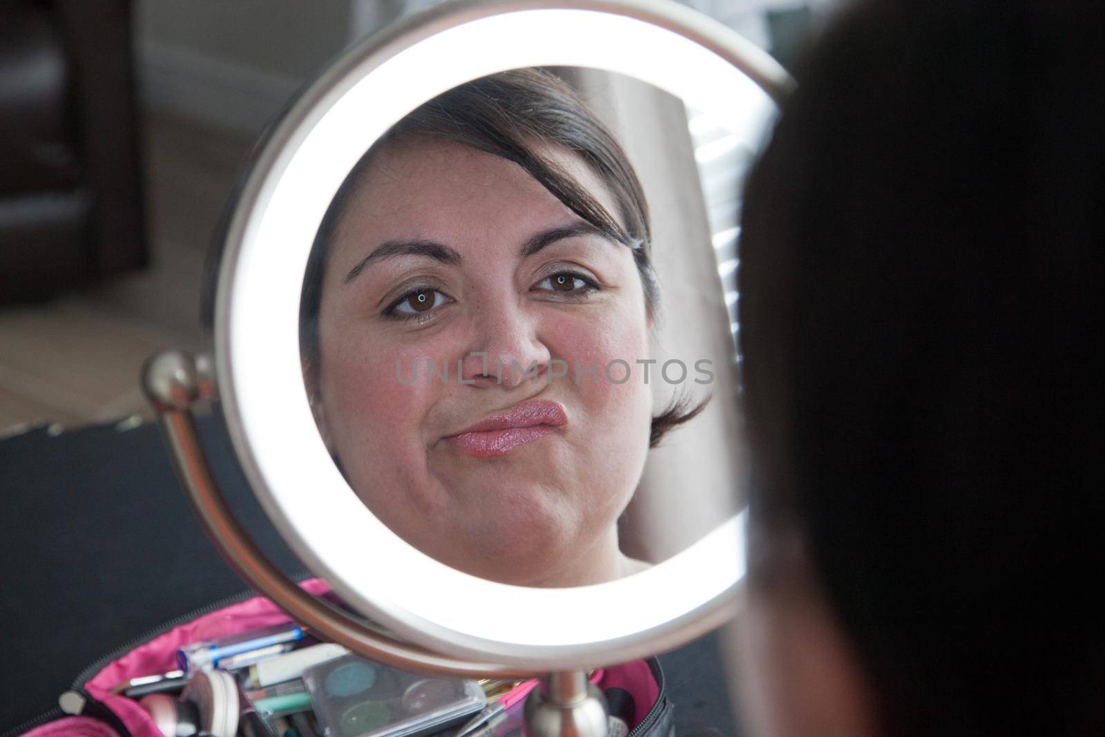  Woman makes a wrinkly unhappy face with her reflection in the mirror 