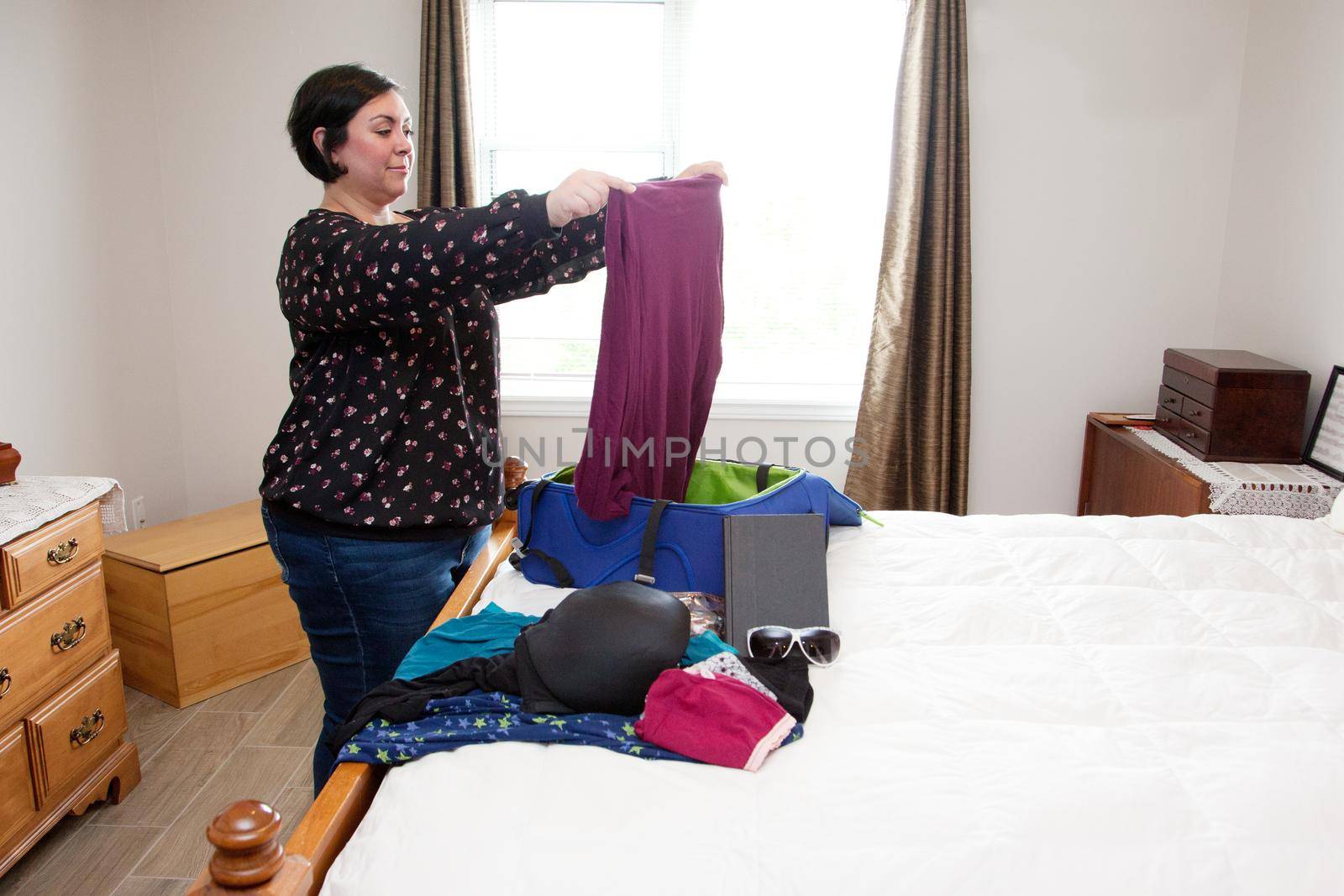 Folding clothes into a suitcase, a woman smiles as she prepares for a journey 