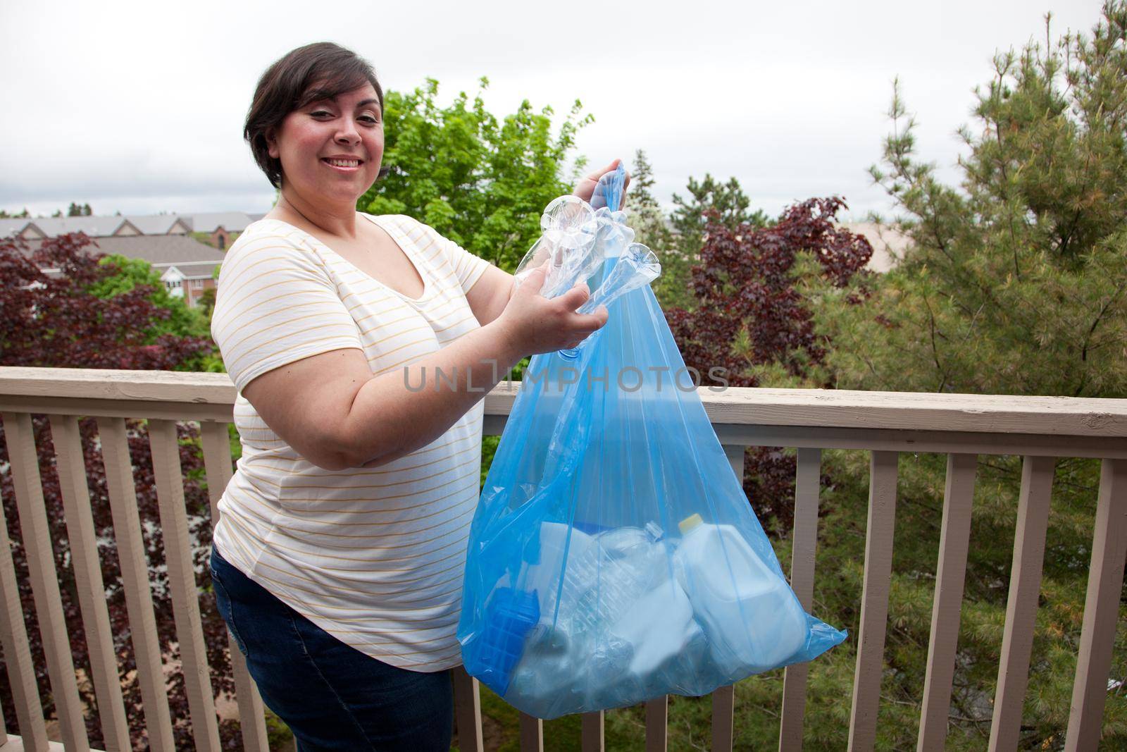 Girl shows off her blue bag of sorted plastics and papers outside 