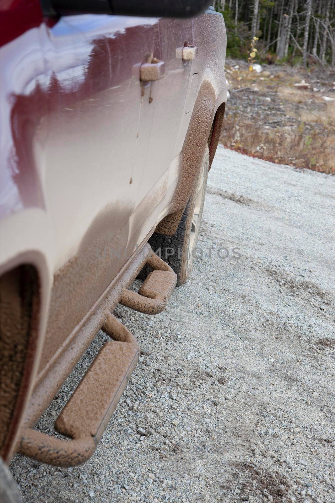 side of a red pickup truck covered with mud from off roading 