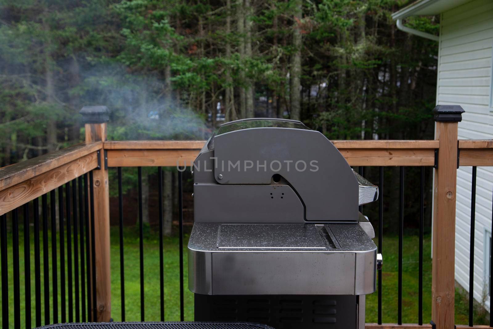  a metal bbq unit is smoking or steaming away cooking food with nobody there 
