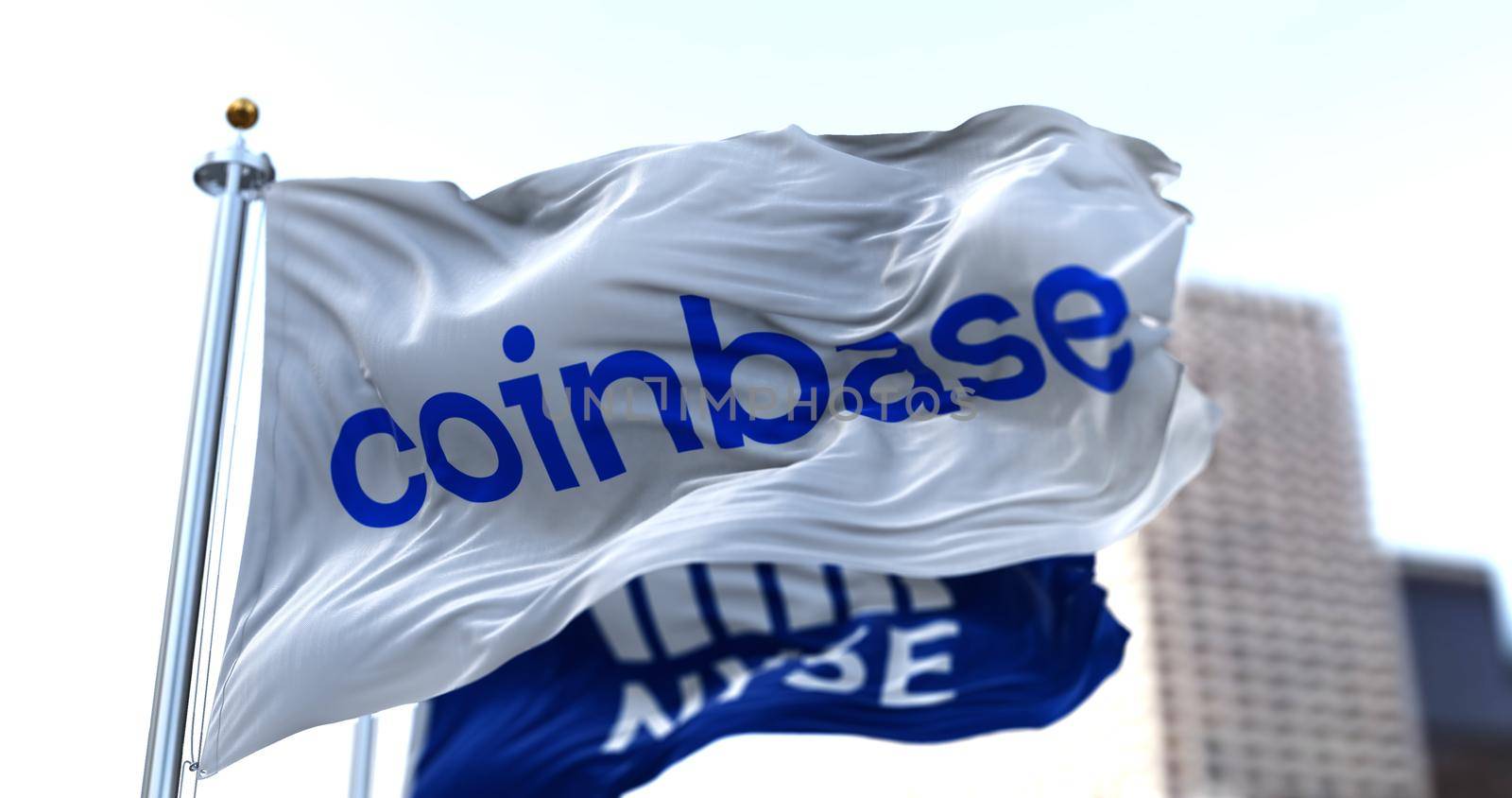 New York, USA, April 14 2021: Flags of Coinbase and NYSE flying in the wind. On April 14, 2021, Coinbase went public on the Nasdaq exchange via a direct stock listing