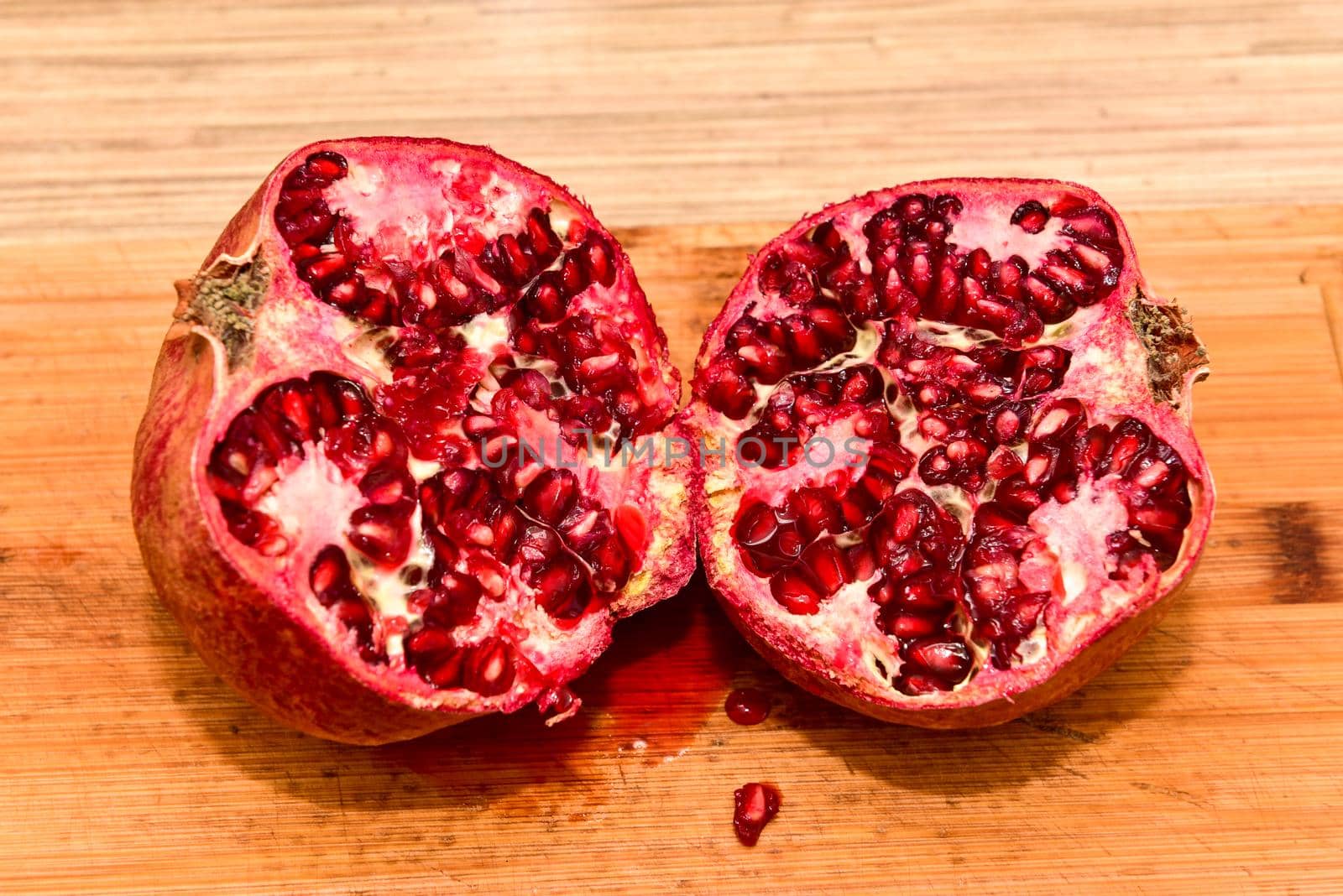 Halved red ripe pomegranate fruits on a wooden board. Natural pomegranate closeup.
