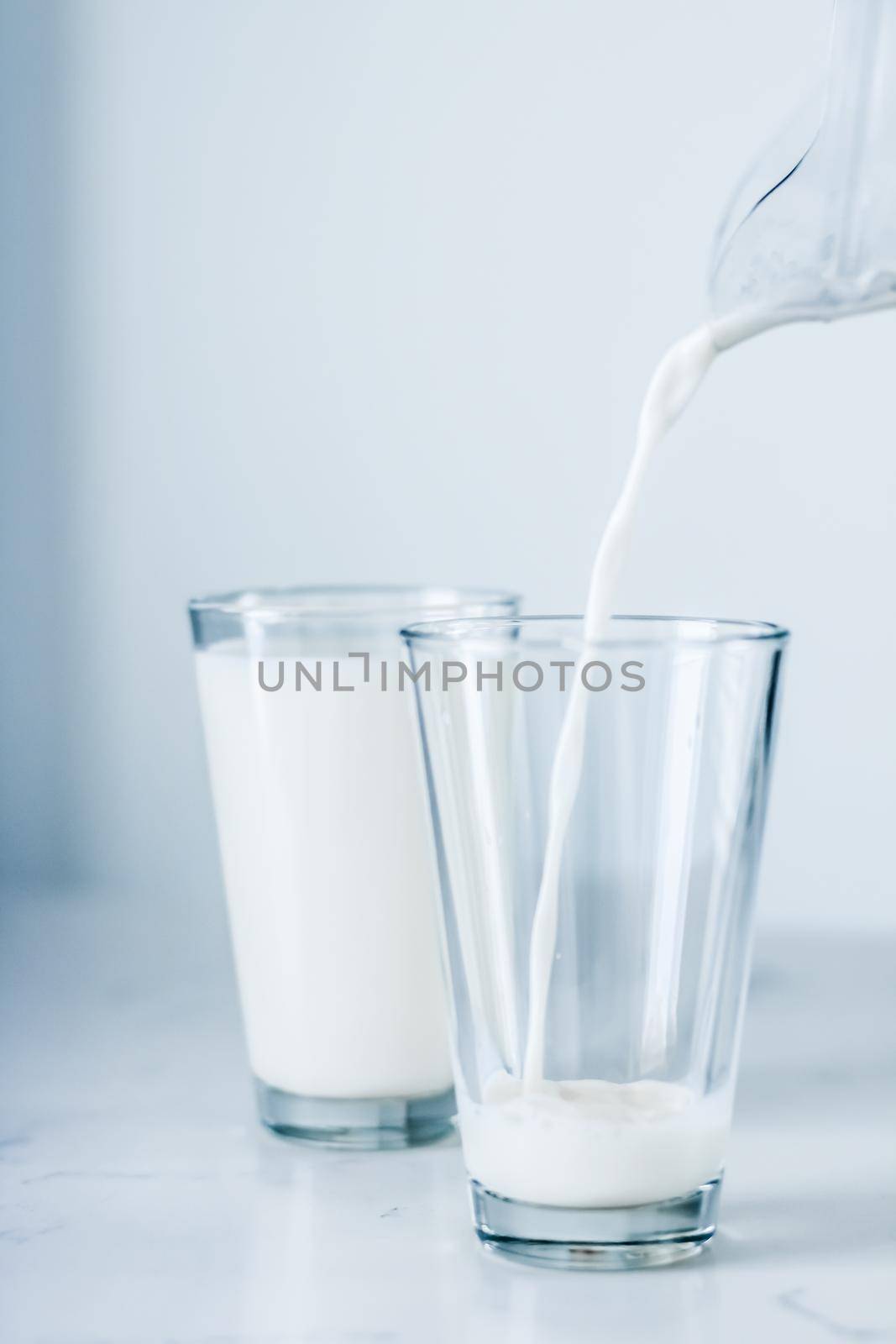 Dairy, healthy nutrition and breakfast concept - World Milk Day, pouring into glass on marble table