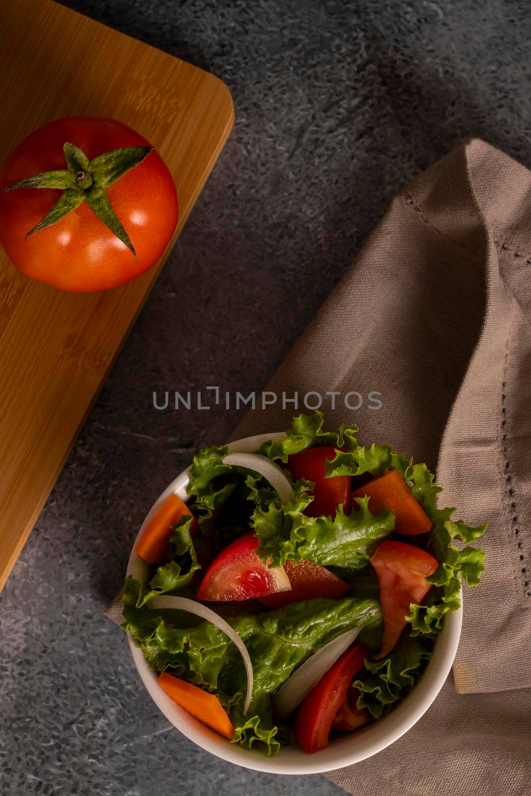 Tomatoes in salad inside a white bowl on grayish background