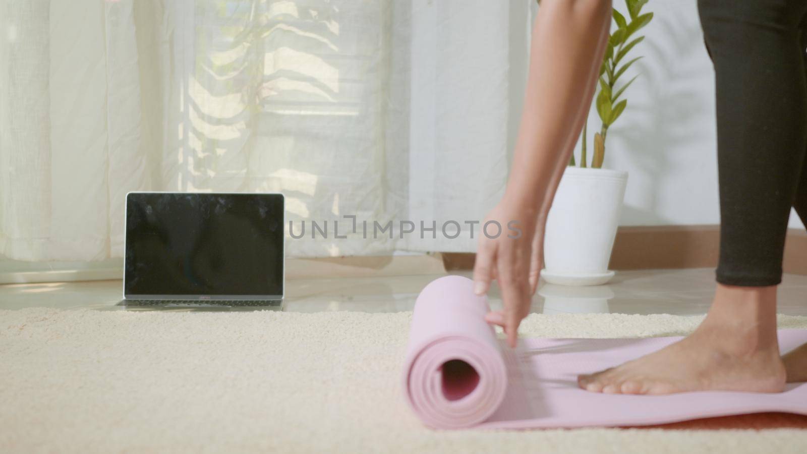 woman rolling fitness yoga pink mat before sports practice for exercise by Sorapop