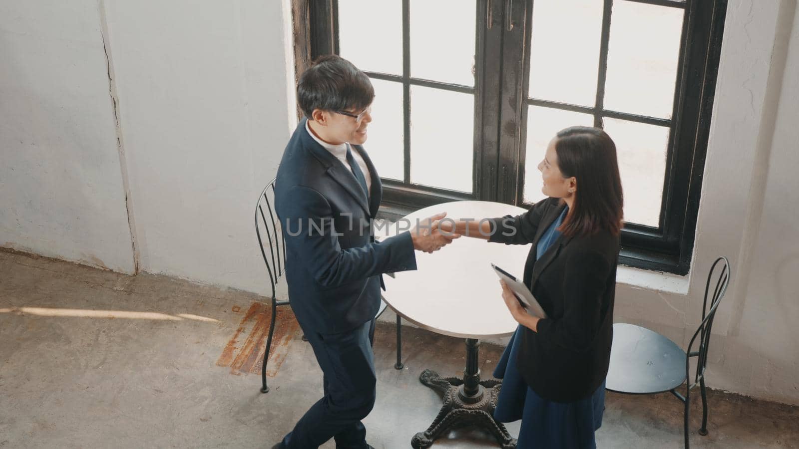 Top view happy two Asian young businessman and woman shaking hands greeting before meeting or negotiation with digital tablet sitting on desk cafe, Businesspeople discussion planning and smile lunch