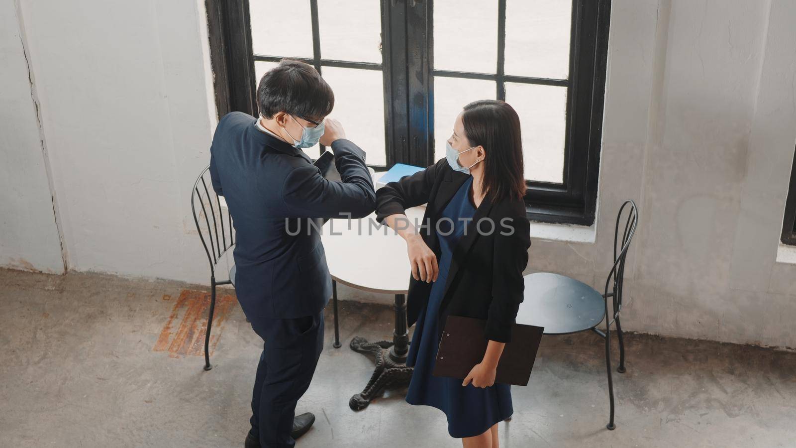 businessman and woman wearing protective face mask greeting say hello by elbow to bump and foot tap by Sorapop