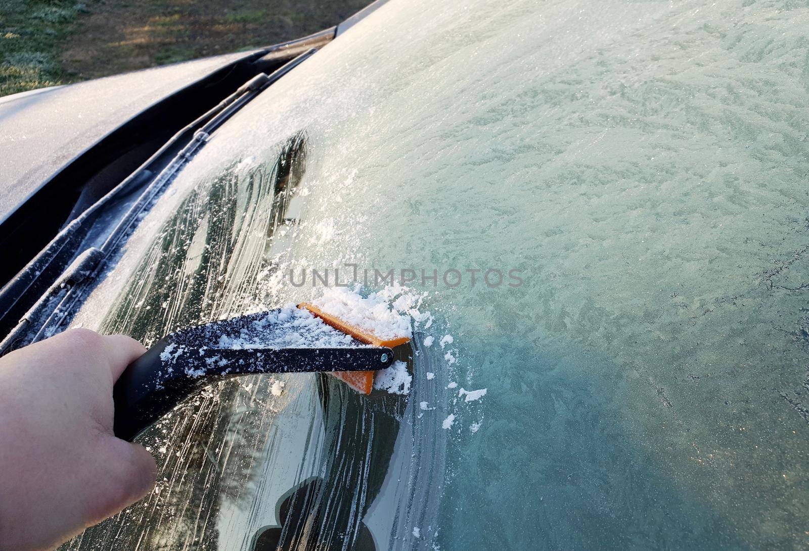 Scraping the ice from windshield of the car by hamik
