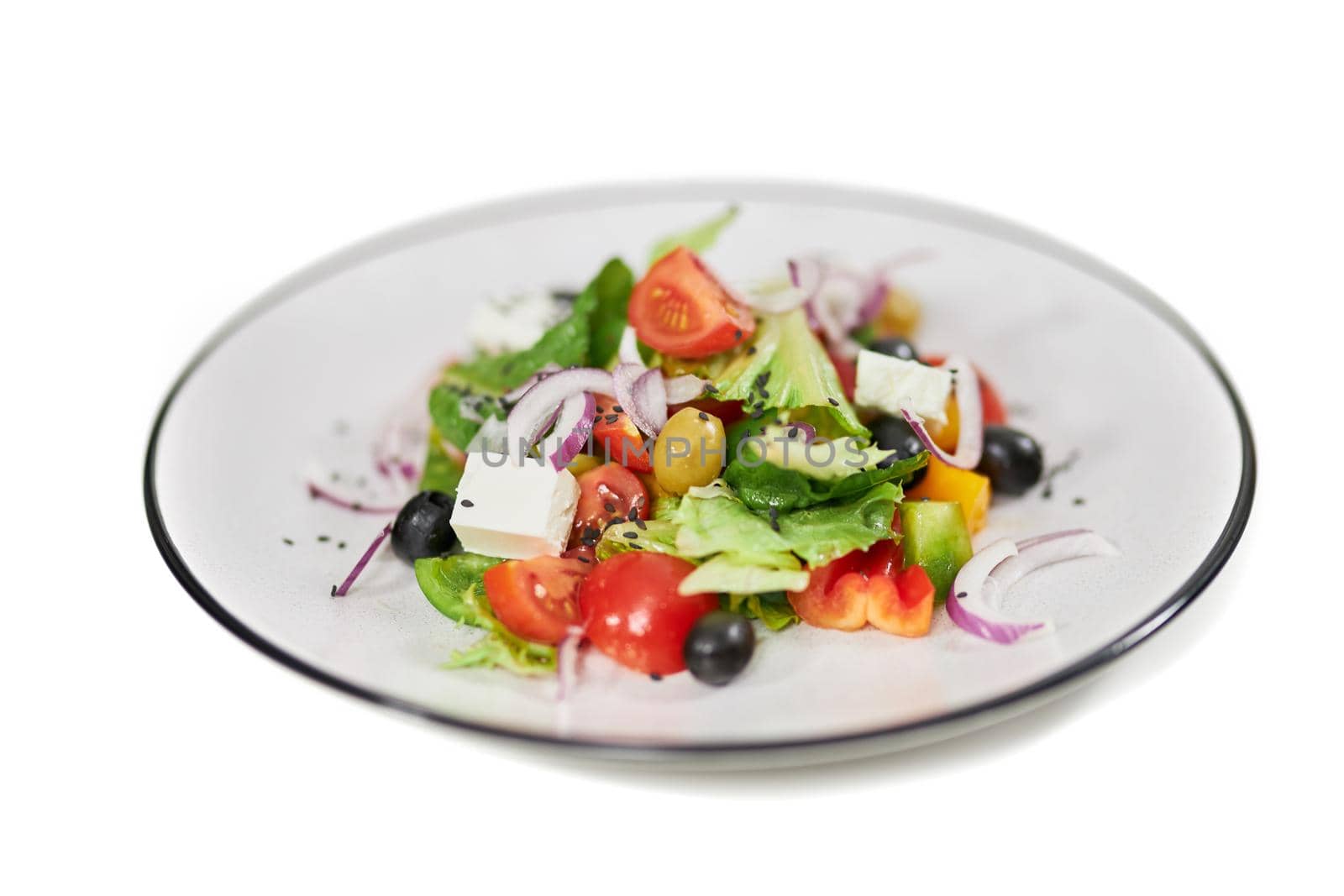 Close up of salad with tomatoes,olives, feta cheese, onion and fresh greens in white background. Concept of delicious vegetables with healthy ingredients for weight loss.