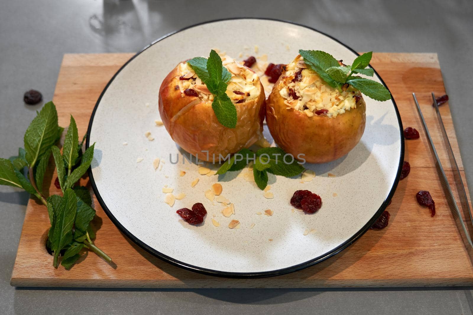 Top view close up of white plate with tasty baked apples with cottage cheese and with fragrant mint. Concept of useful appetizing dessert on wooden board. 