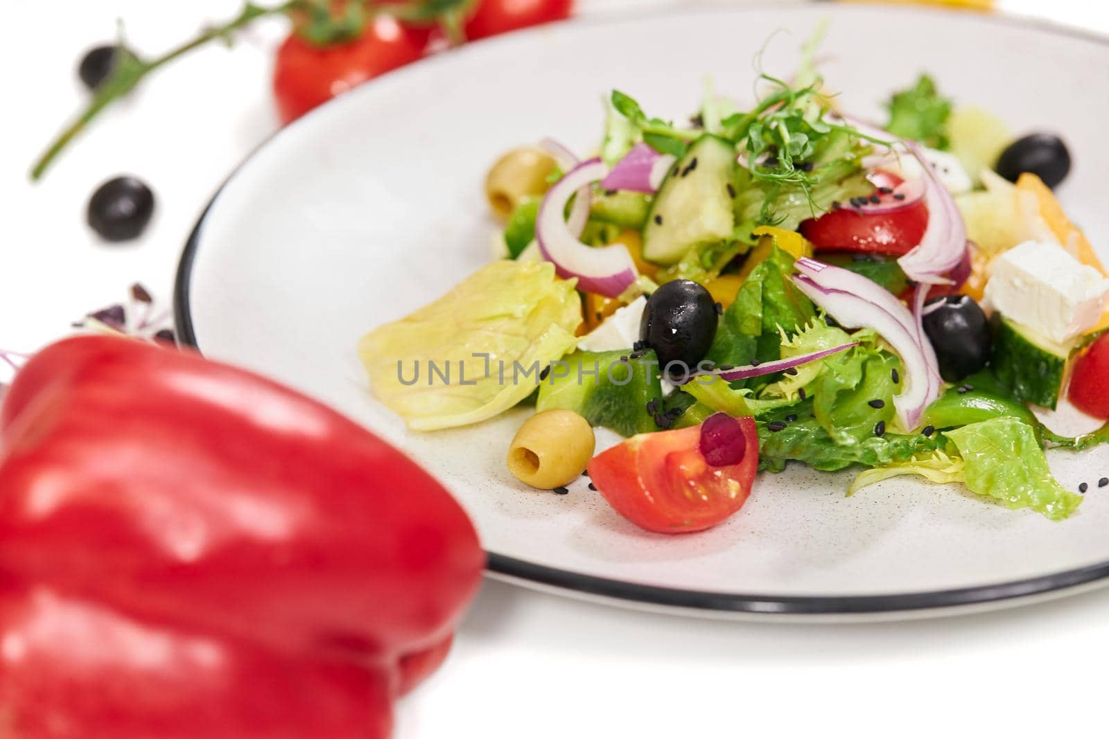 Close up of delicious vegetables salad with appetizing tomatoes,olives,greens,onions and feta cheese on white background. Concept of proper nutrition for weight loss.