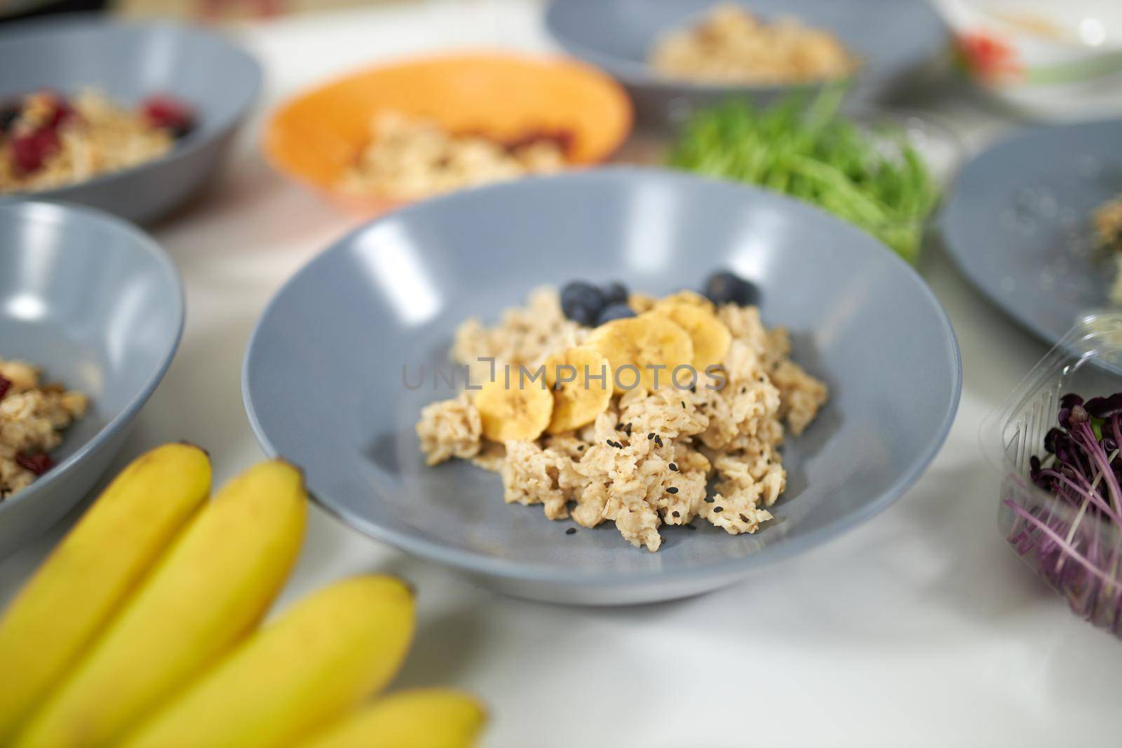 Close up of appetizing porridge with berries and fresh bananas in beautiful blue plate. Concept of menu to maintain body weight or lose weight at home. 