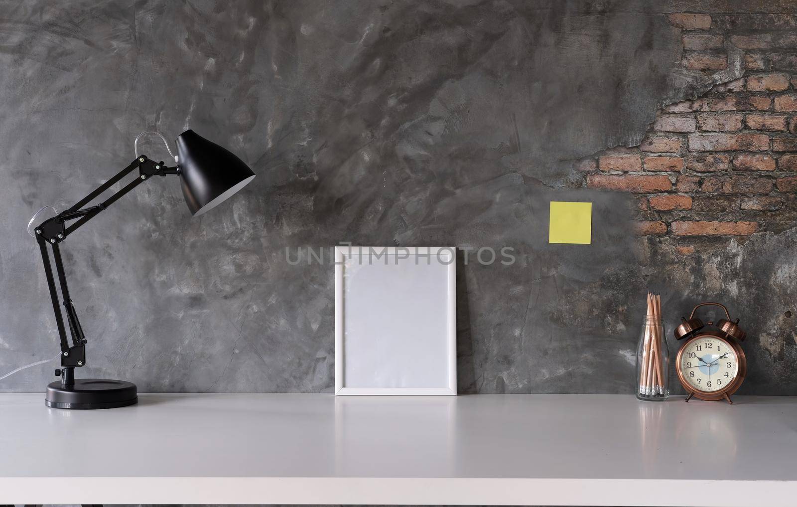 White desk with photo frame, lamp, office supplies, clock in design vase.