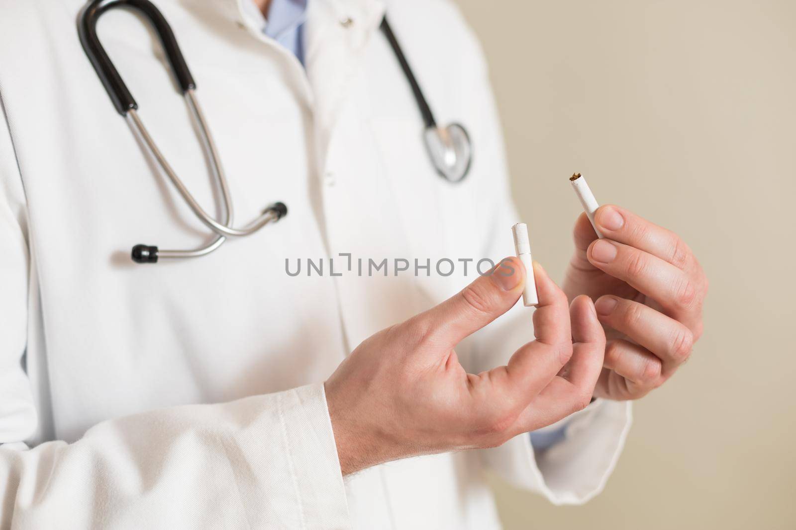 Image of male doctor showing broken cigarette. Stop smoking concept.