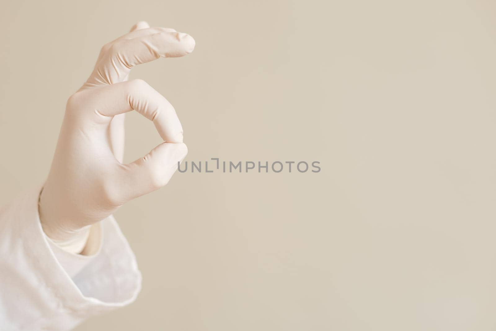 Image of close up hand in protective glove of doctor showing ok sign.