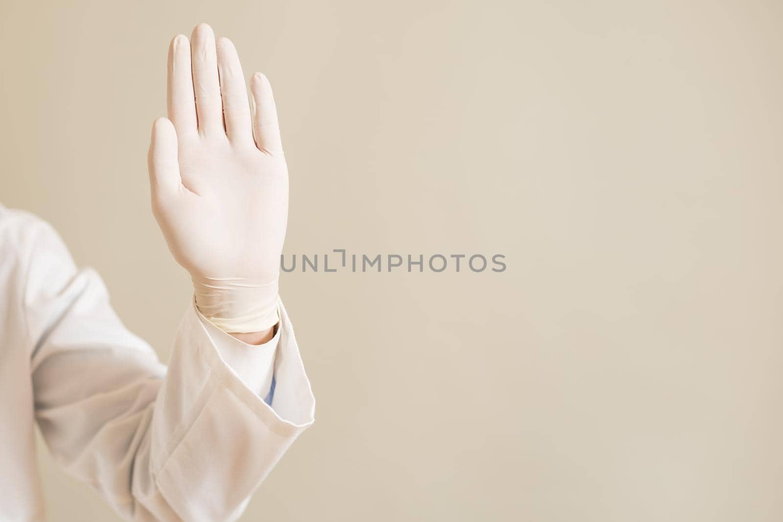 Image of close up hand in protective glove  of doctor showing stop sign.