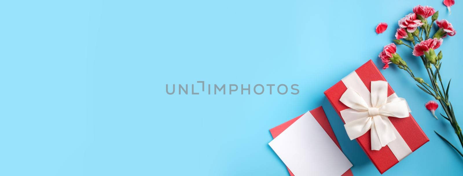 Mother's Day gift. Top view design concept of holiday greeting card with red carnation bouquet on bright blue table background