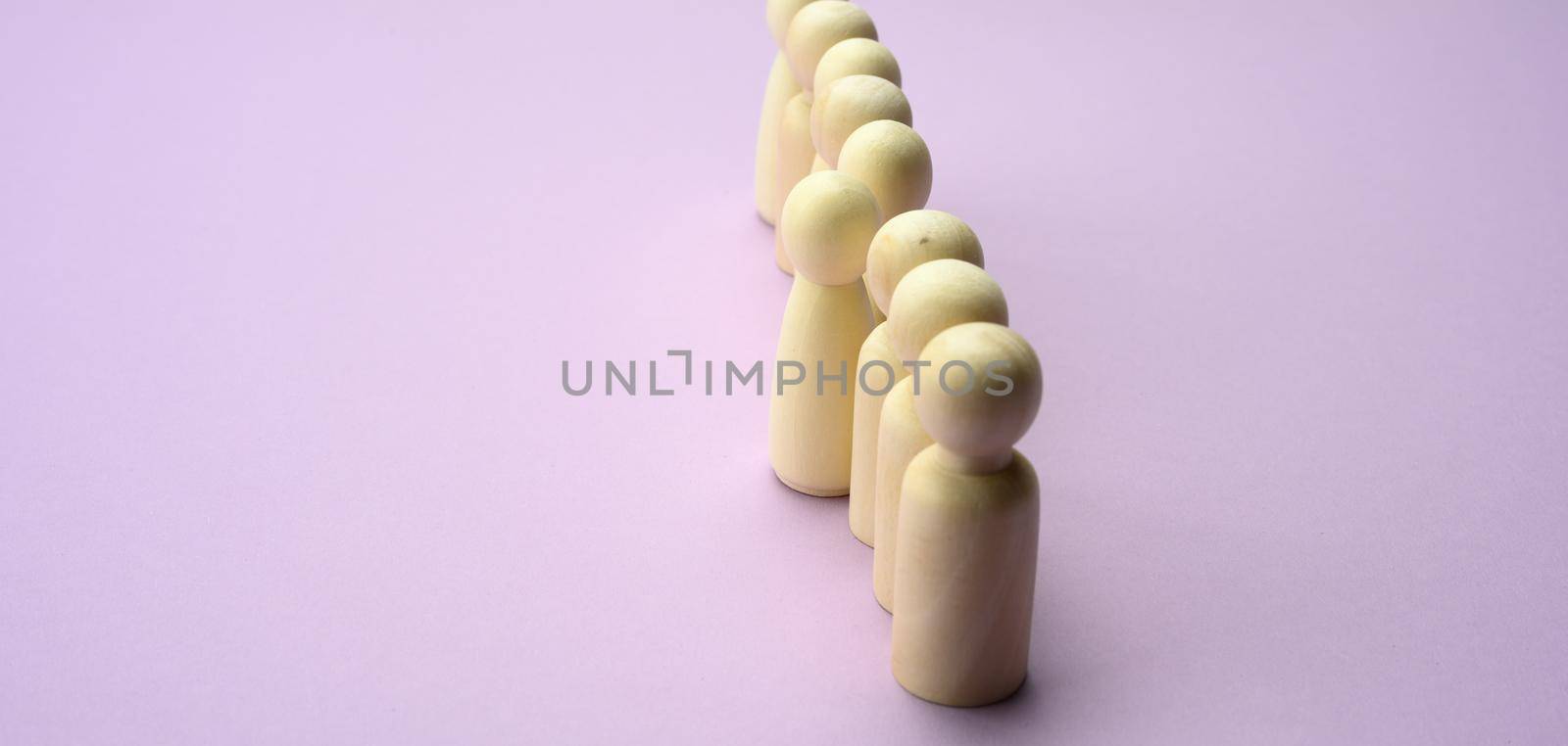 wooden men stand in a row, one figurine sticking out in front. The concept of exclusivity, talent