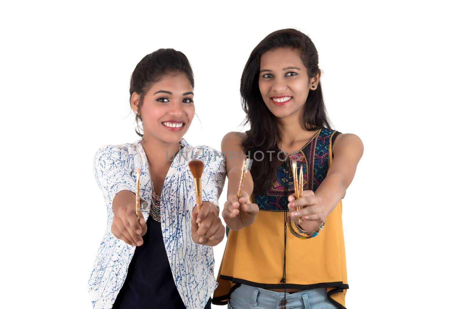 Beautiful young girls enjoying with makeup brushes isolated on white