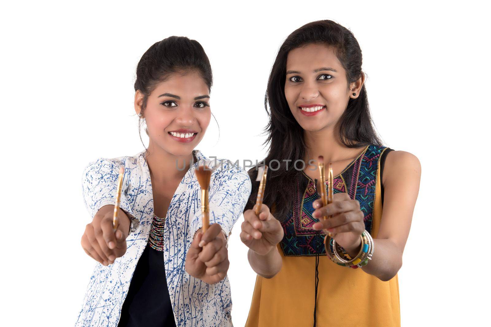 Beautiful young girls enjoying with makeup brushes isolated on white by DipakShelare