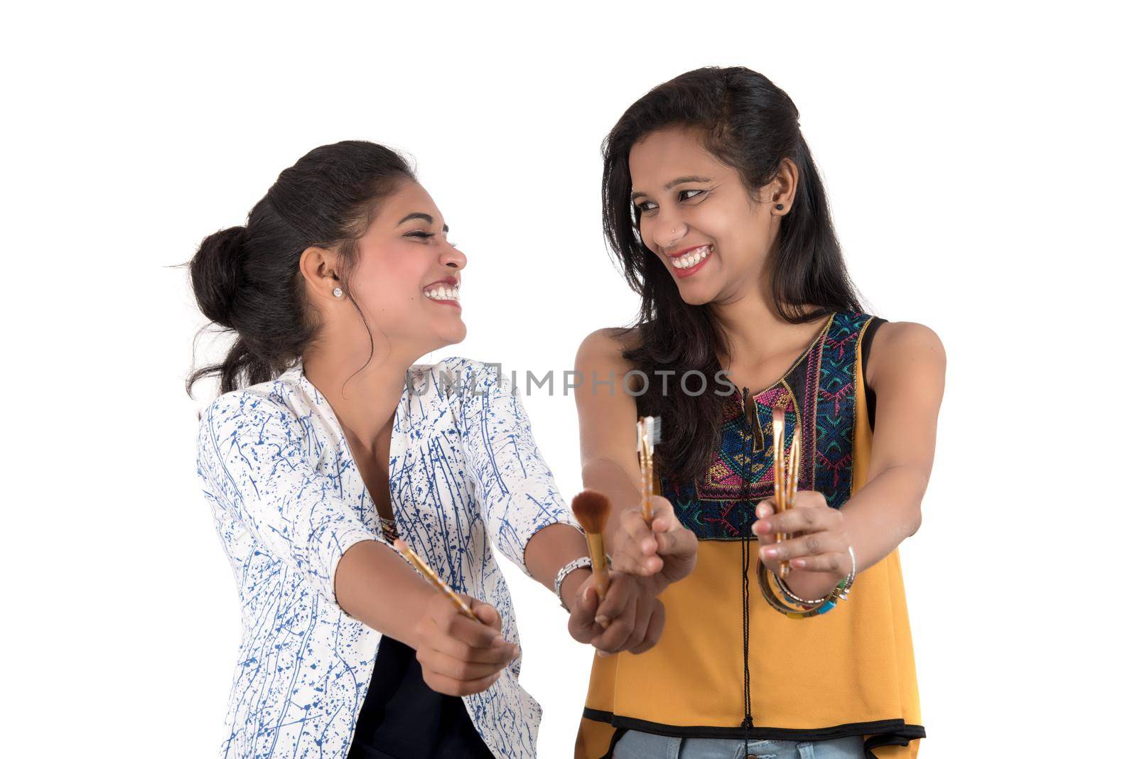 Beautiful young girls enjoying with makeup brushes isolated on white by DipakShelare
