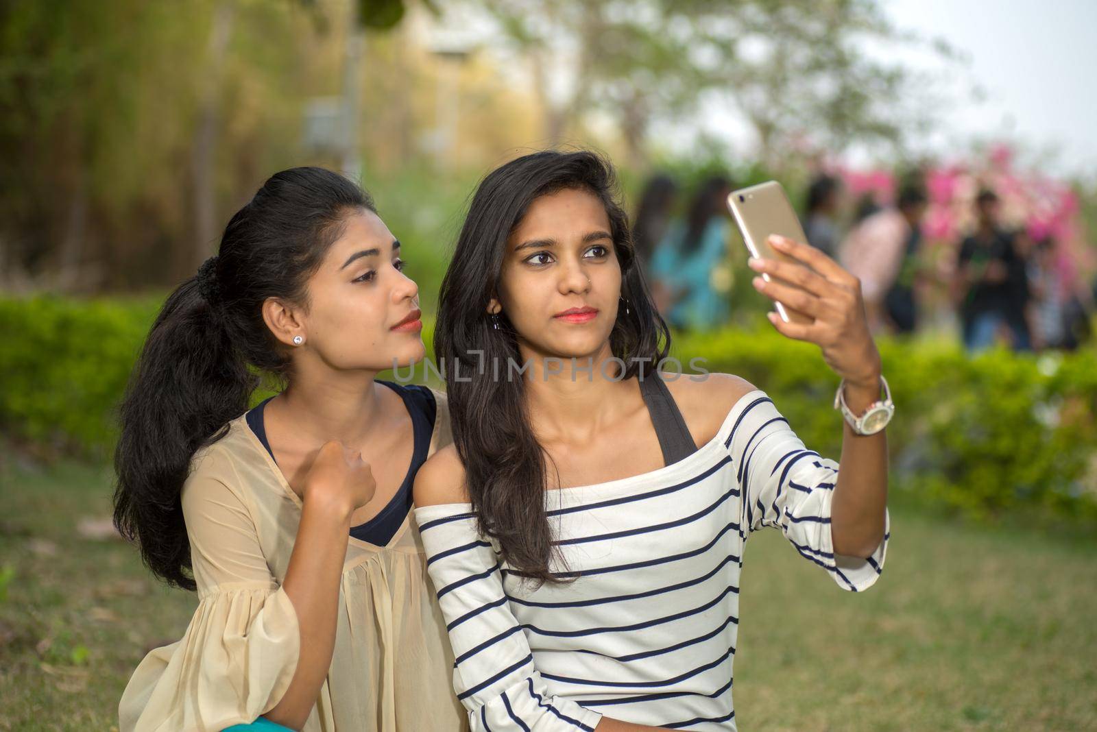 Two beautiful female friends taking selfie with smartphone in outdoors. by DipakShelare