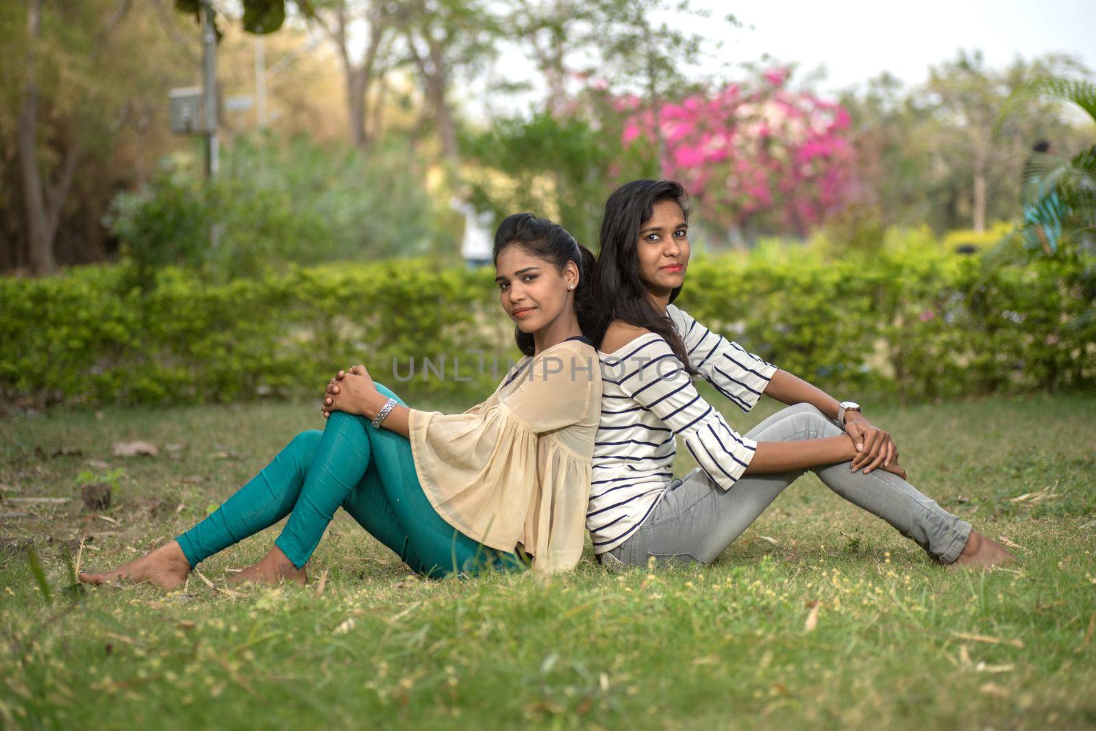 Two young girl friends having fun together in outdoors. Looking at camera.