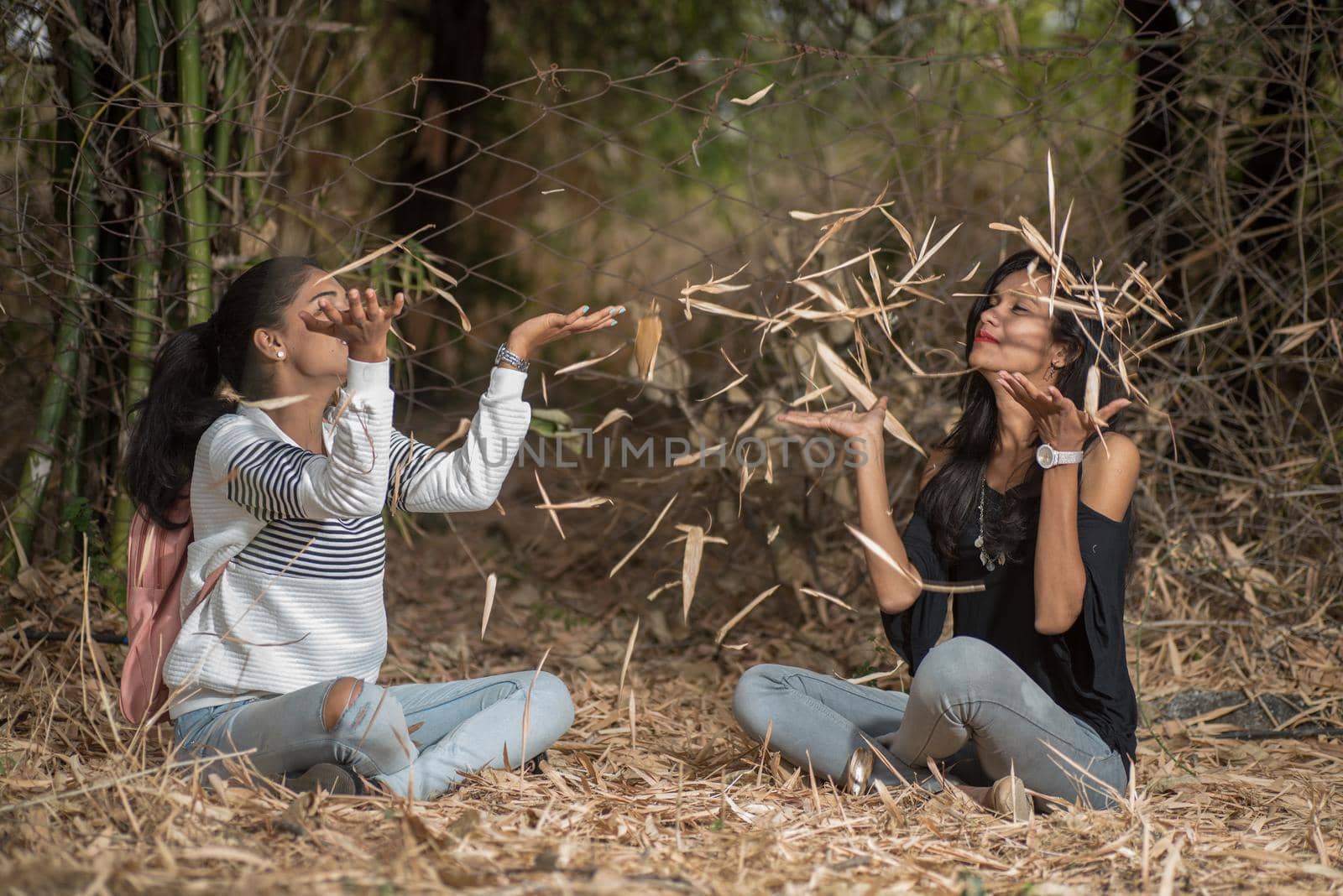 Happy girls playing with fallen leaves in park