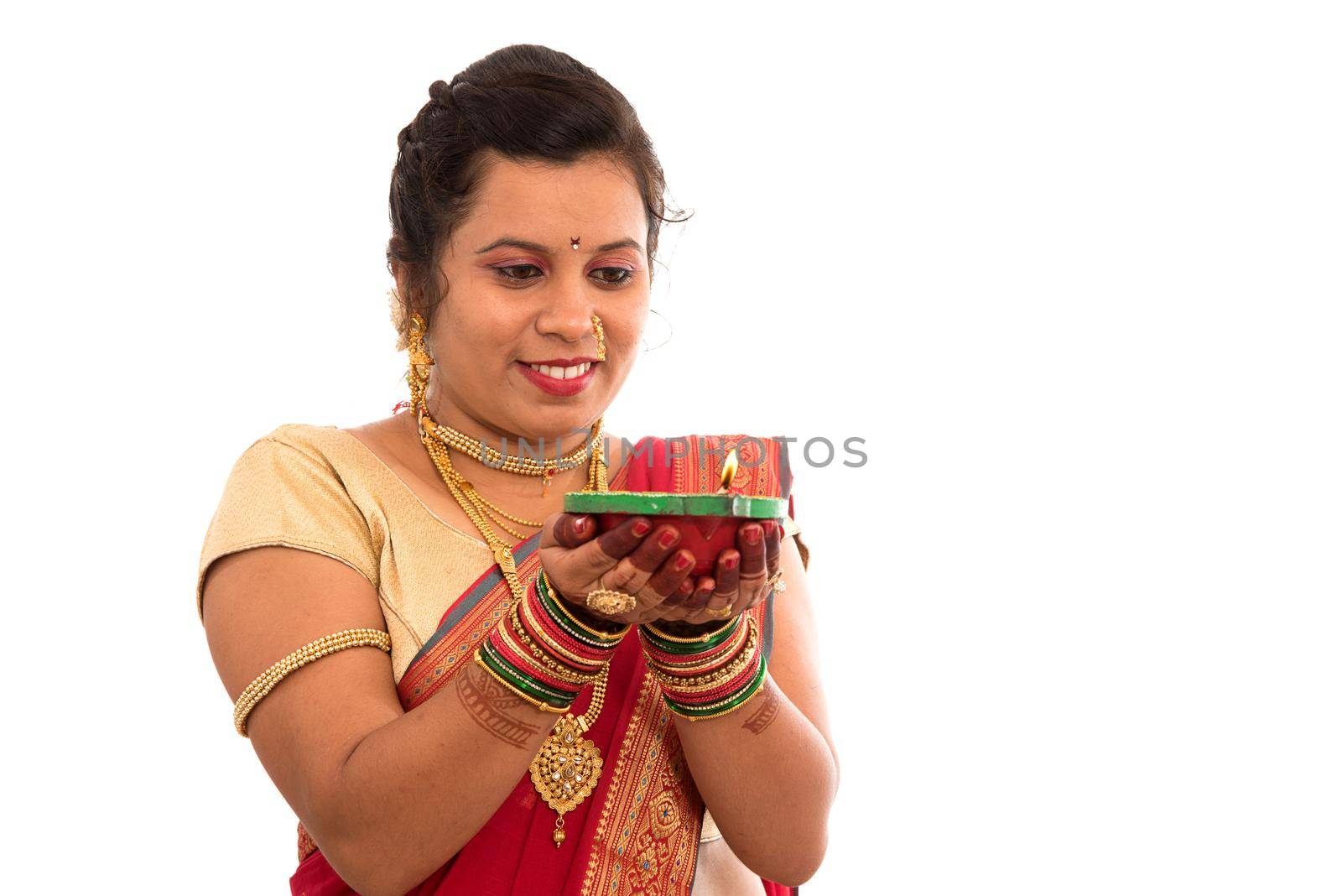 Portrait of a Indian Traditional Girl holding pooja thali with diya during festival of light on white background. Diwali or deepavali