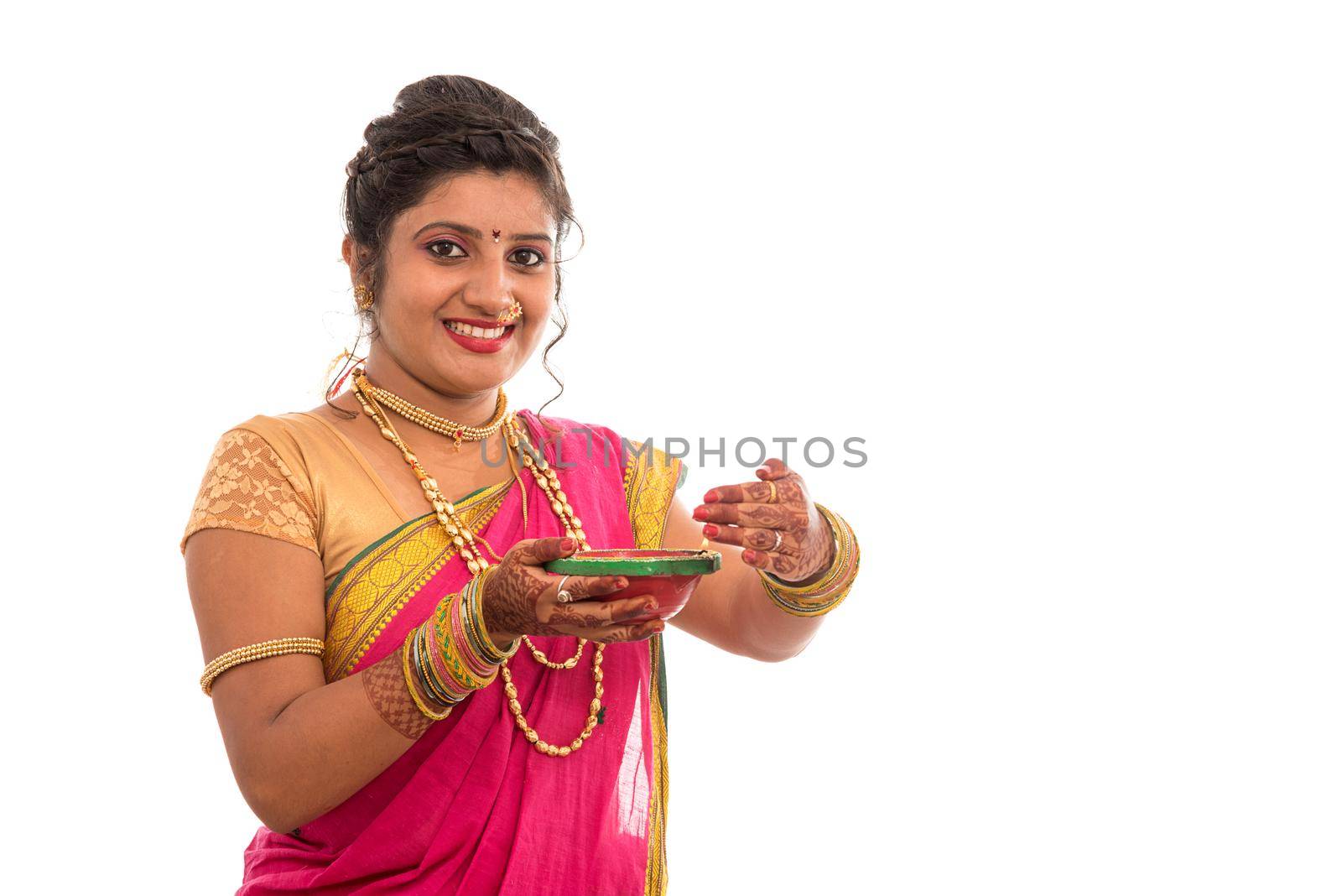 Portrait of a Indian Traditional Girl holding pooja thali with diya during festival of light on white background. Diwali or deepavali