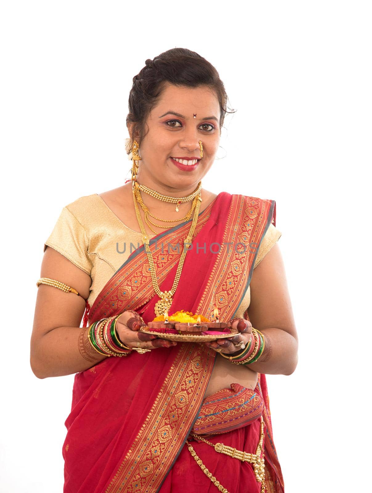 Portrait of a Indian Traditional Girl holding pooja thali with diya during festival of light on white background. Diwali or deepavali