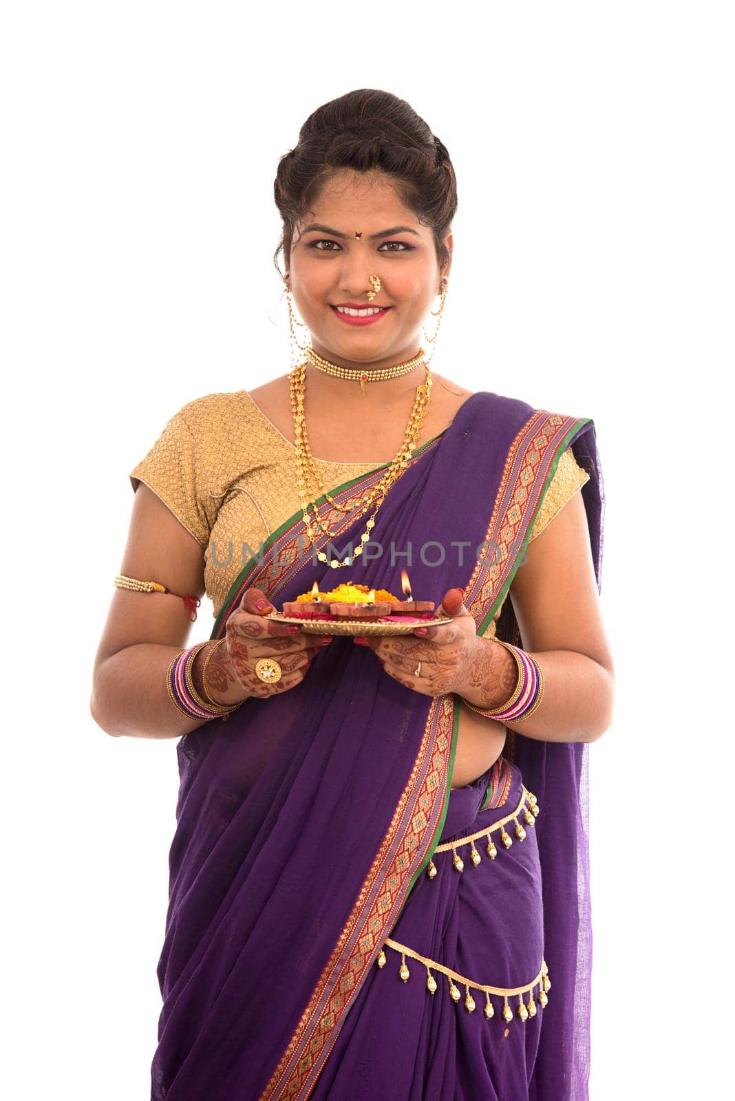 Portrait of a Indian Traditional Girl holding pooja thali with diya during festival of light on white background. Diwali or deepavali